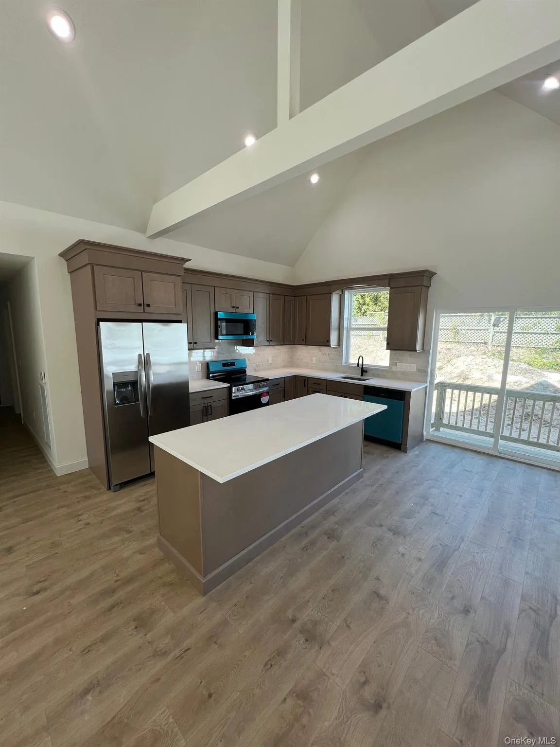 Kitchen with a sink, light countertops, light wood finished floors, stainless steel appliances, and a kitchen island Kitchen with a sink, light countertops, light wood finished floors, stainless steel appliances, and a kitchen island