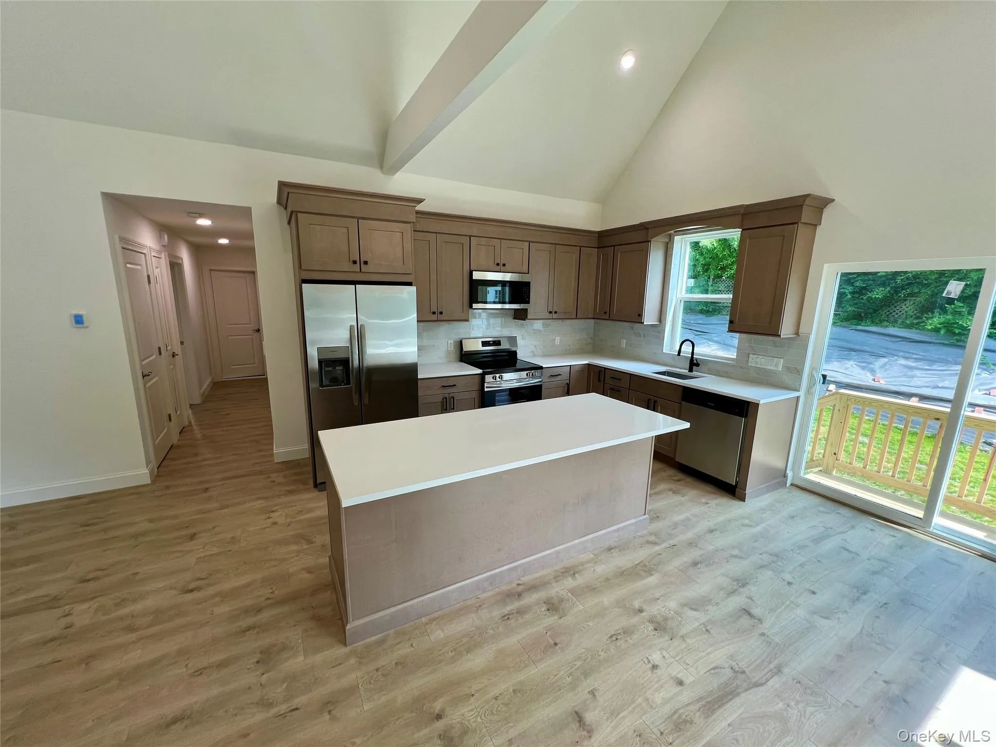 Kitchen featuring appliances with stainless steel finishes, tasteful backsplash, light wood-style flooring, light countertops, and a center island Kitchen featuring appliances with stainless steel finishes, tasteful backsplash, light wood-style flooring, light countertops, and a center island