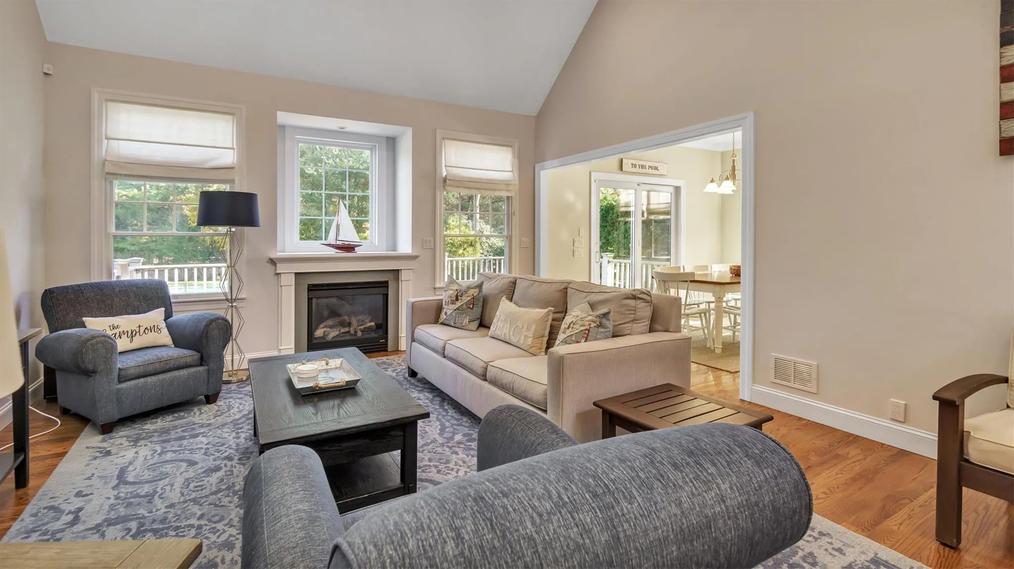 Living room featuring lofted ceiling, wood finished floors, a healthy amount of sunlight, and visible vents Living room featuring lofted ceiling, wood finished floors, a healthy amount of sunlight, and visible vents