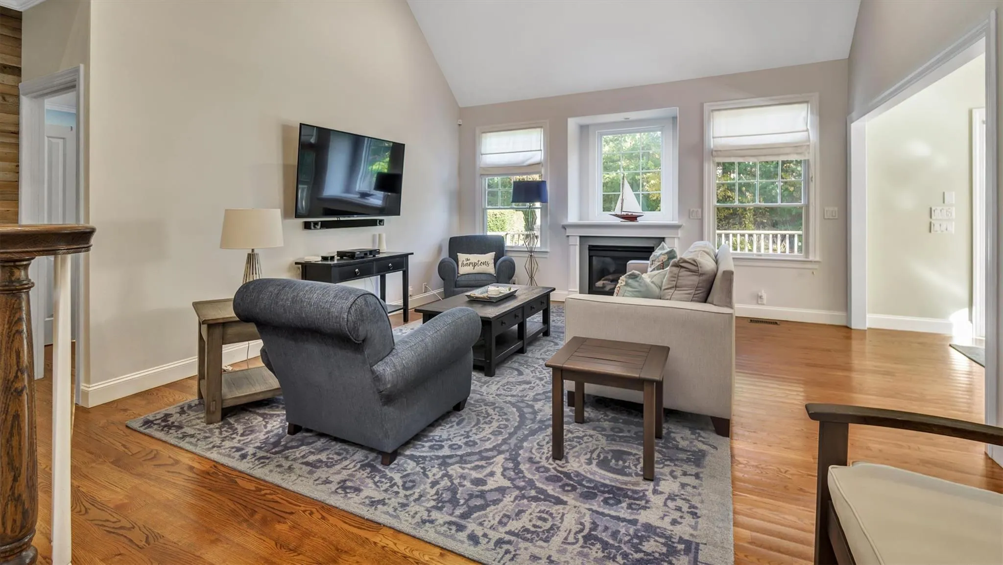 Living area with a glass covered fireplace, baseboards, lofted ceiling, and wood finished floors Living area with a glass covered fireplace, baseboards, lofted ceiling, and wood finished floors