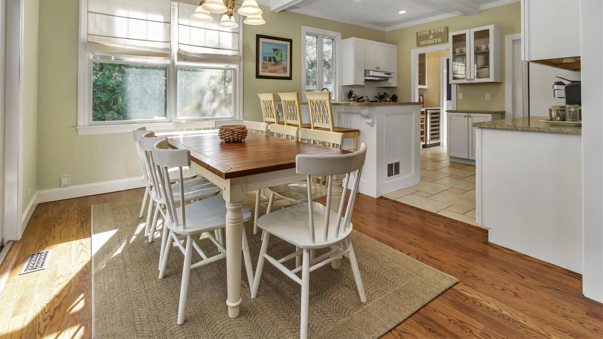 Dining area featuring beverage cooler, visible vents, light wood-style flooring, and baseboards Dining area featuring beverage cooler, visible vents, light wood-style flooring, and baseboards