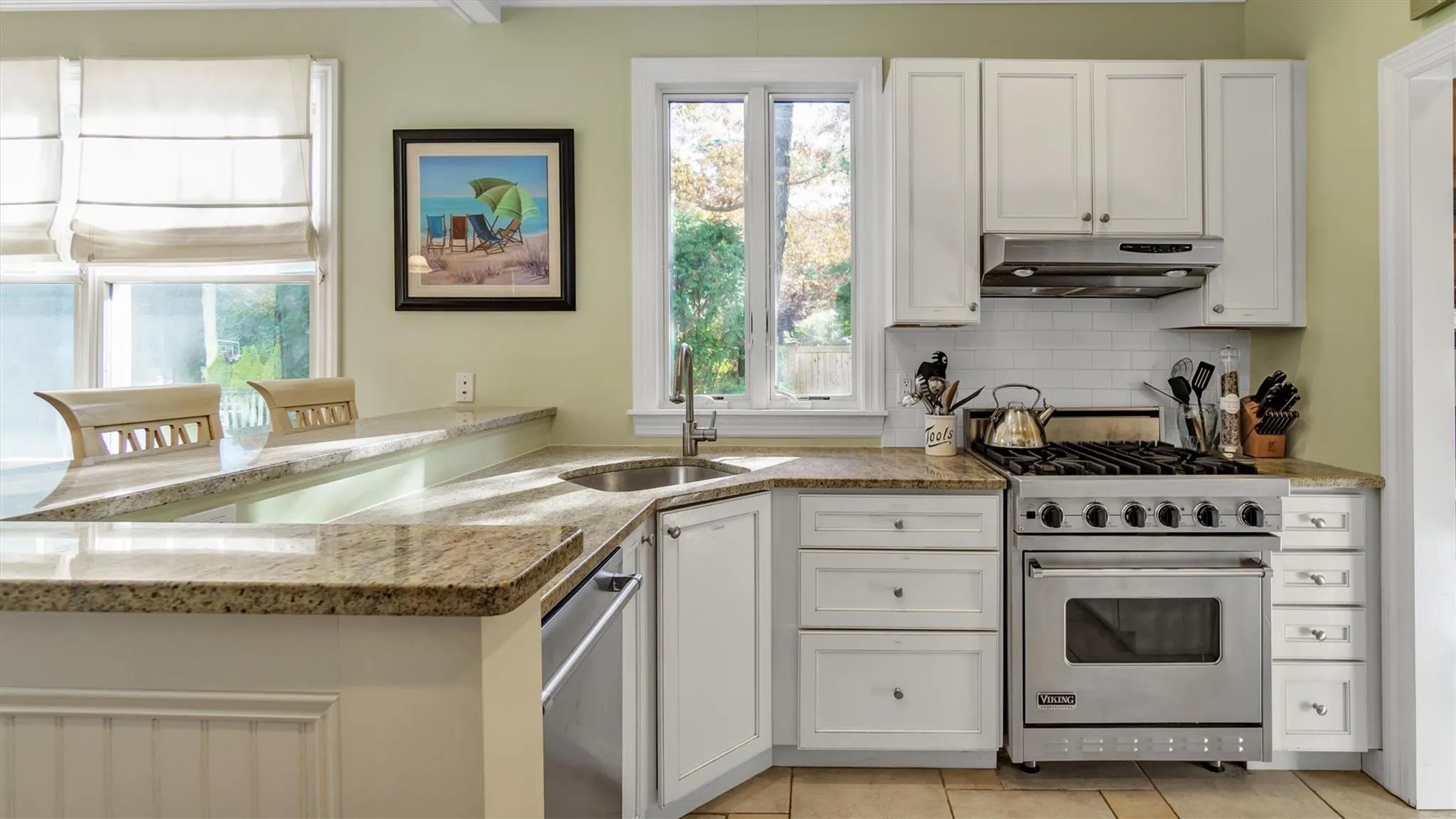 Kitchen with under cabinet range hood, a sink, backsplash, stainless steel appliances, and light tile patterned floors Kitchen with under cabinet range hood, a sink, backsplash, stainless steel appliances, and light tile patterned floors
