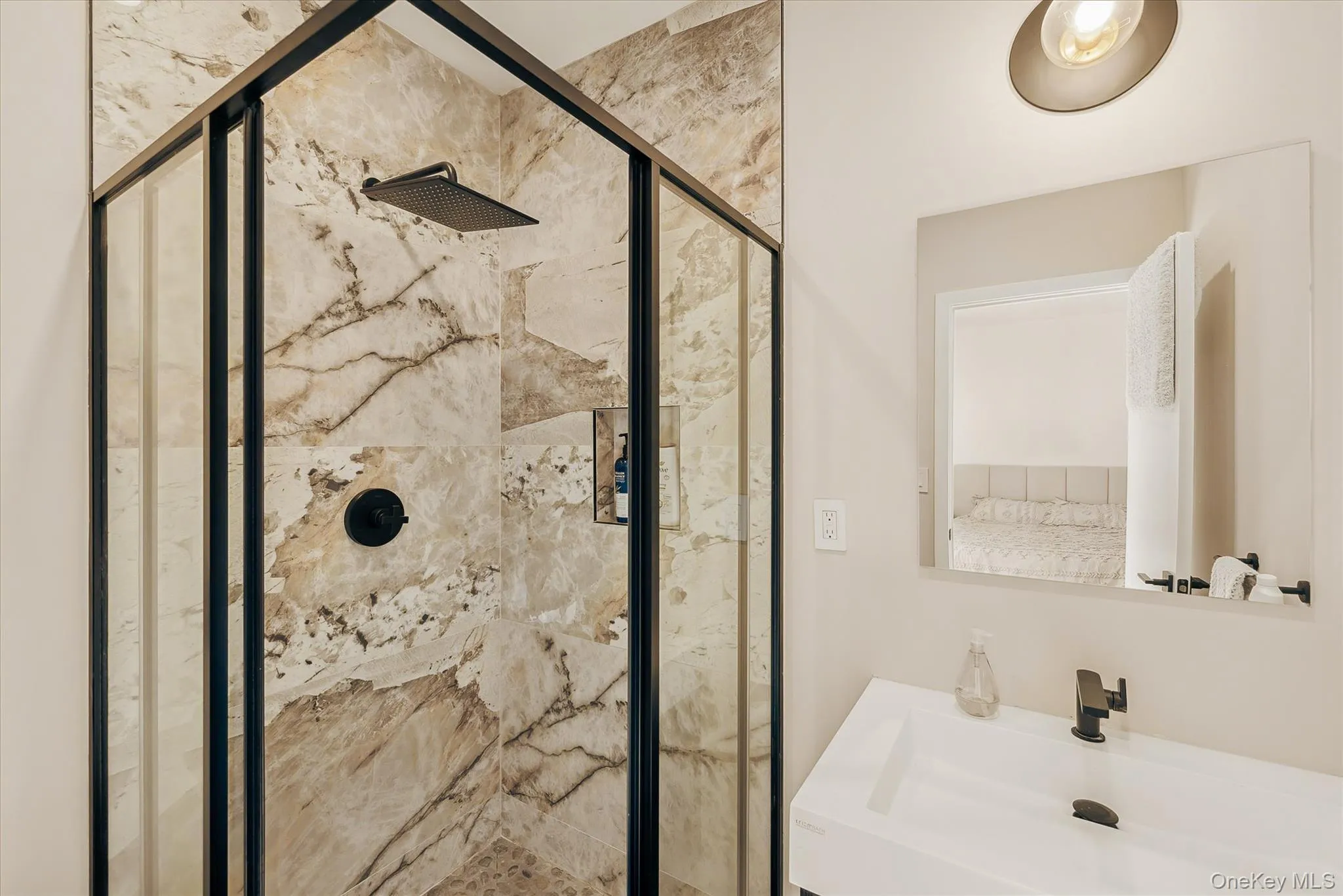 Bathroom featuring a sink and a shower stall Bathroom featuring a sink and a shower stall