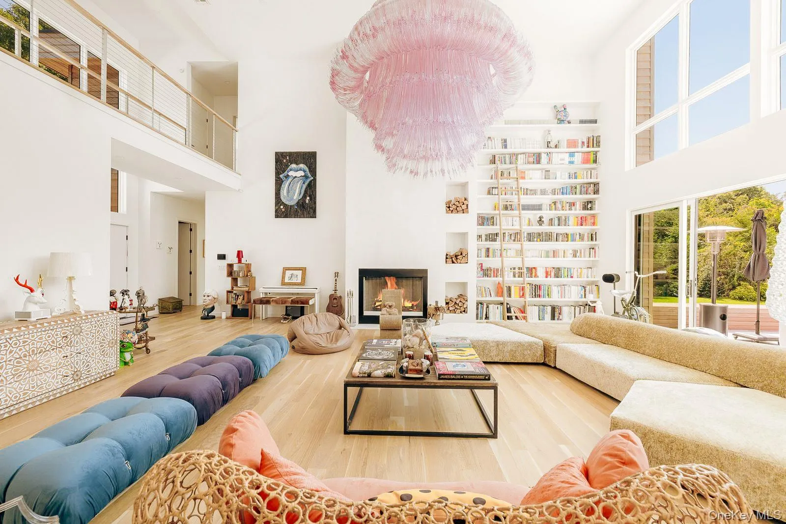 Living room with a high ceiling, a warm lit fireplace, and wood finished floors Living room with a high ceiling, a warm lit fireplace, and wood finished floors
