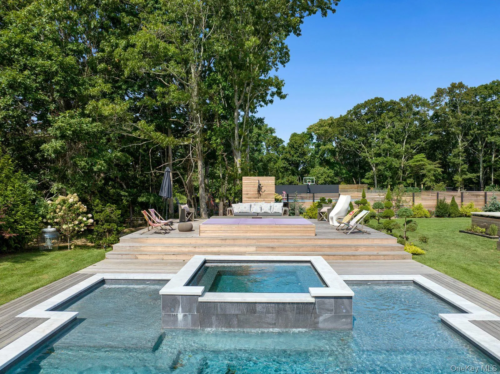 View of swimming pool featuring a lawn, a pool with connected hot tub, a wooden deck, and fence View of swimming pool featuring a lawn, a pool with connected hot tub, a wooden deck, and fence