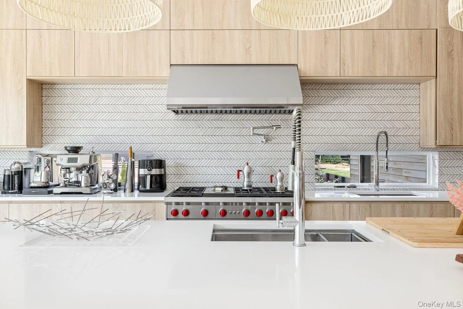 Kitchen with light brown cabinetry, ventilation hood, and light countertops Kitchen with light brown cabinetry, ventilation hood, and light countertops