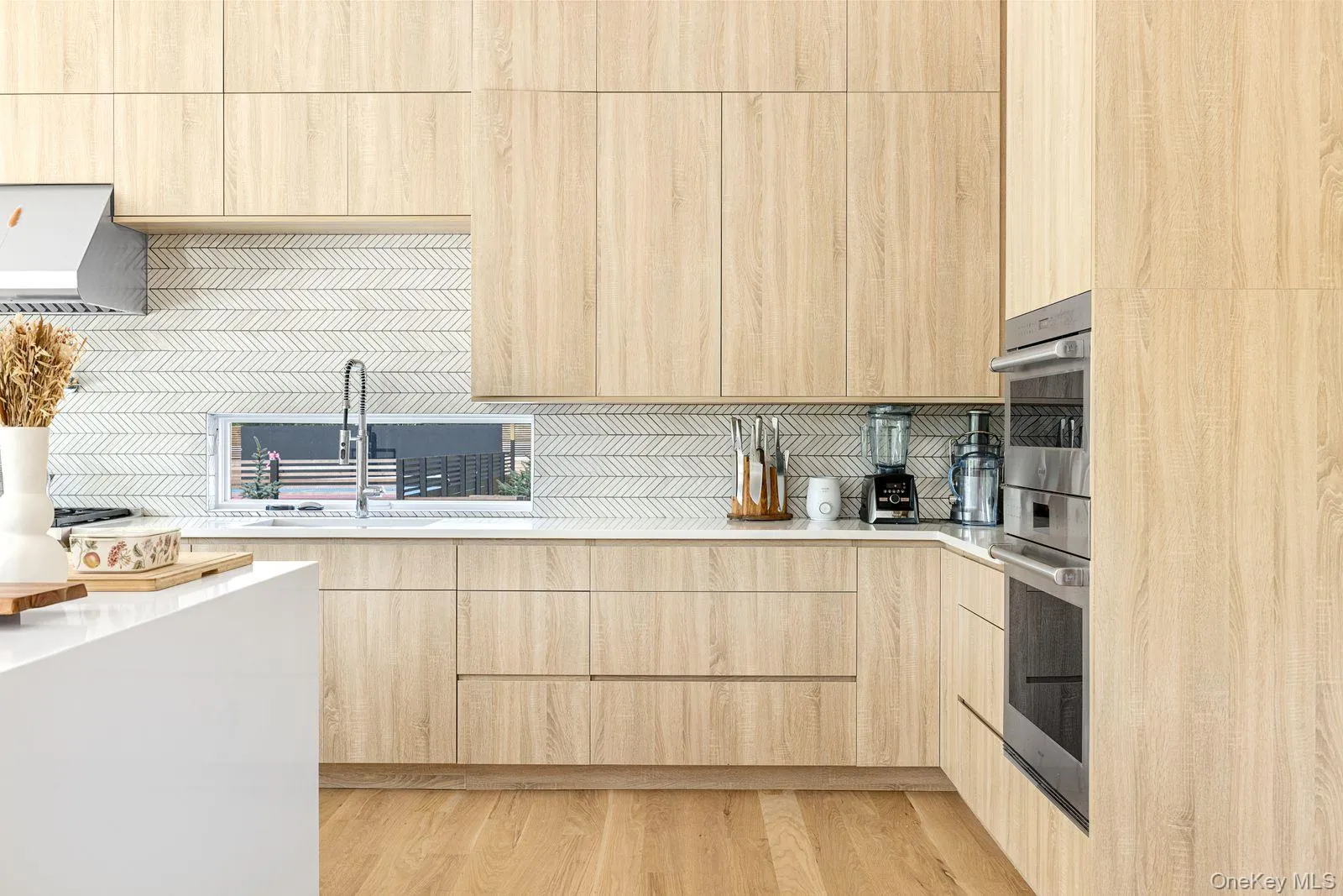 Kitchen with light wood-style floors, modern cabinets, light brown cabinetry, and light countertops Kitchen with light wood-style floors, modern cabinets, light brown cabinetry, and light countertops