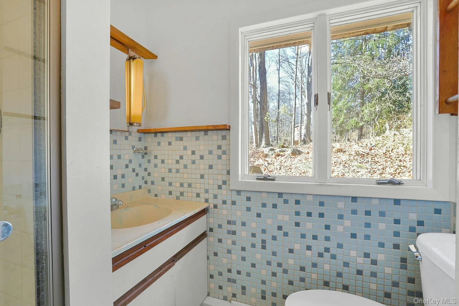 The tiled private primary bathroom has a glass shower. The tiled private primary bathroom has a glass shower.