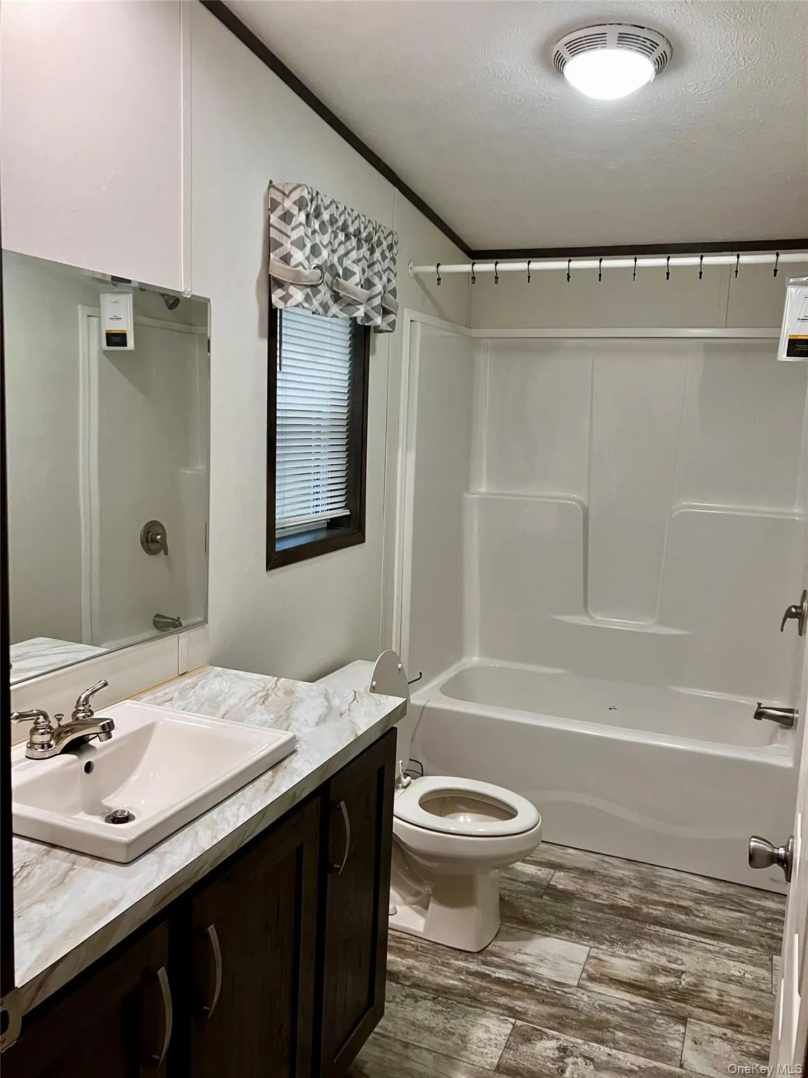 Master Bathroom combination, a textured ceiling, wood finished floors, toilet, and vanity Master Bathroom combination, a textured ceiling, wood finished floors, toilet, and vanity