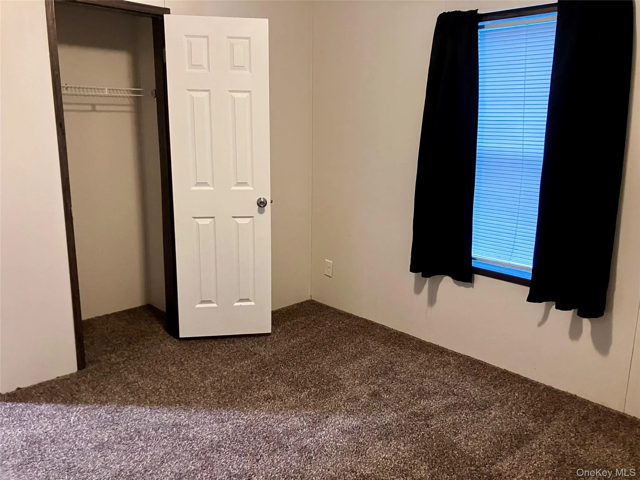 Unfurnished bedroom featuring a closet and dark colored carpet Unfurnished bedroom featuring a closet and dark colored carpet