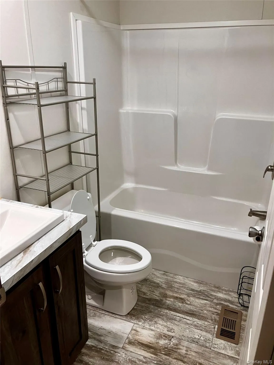 Bathroom featuring toilet, vanity, shower / tub combination, wood finished floors, and visible vents Bathroom featuring toilet, vanity, shower / tub combination, wood finished floors, and visible vents