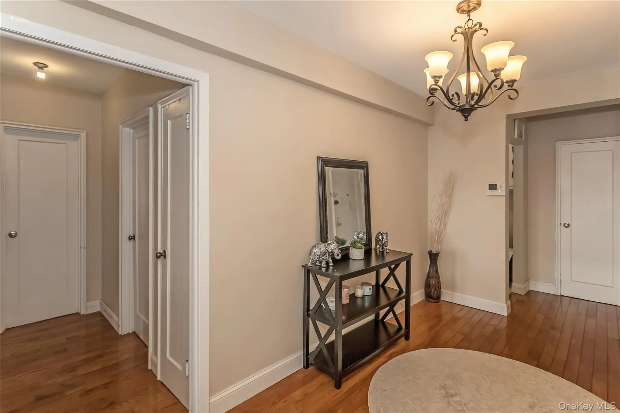 Hall with baseboards, an inviting chandelier, and wood finished floors Hall with baseboards, an inviting chandelier, and wood finished floors
