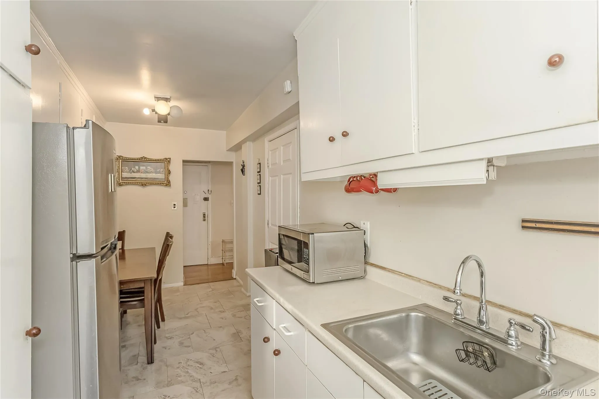 Kitchen featuring light countertops, white cabinets, appliances with stainless steel finishes, and a sink Kitchen featuring light countertops, white cabinets, appliances with stainless steel finishes, and a sink