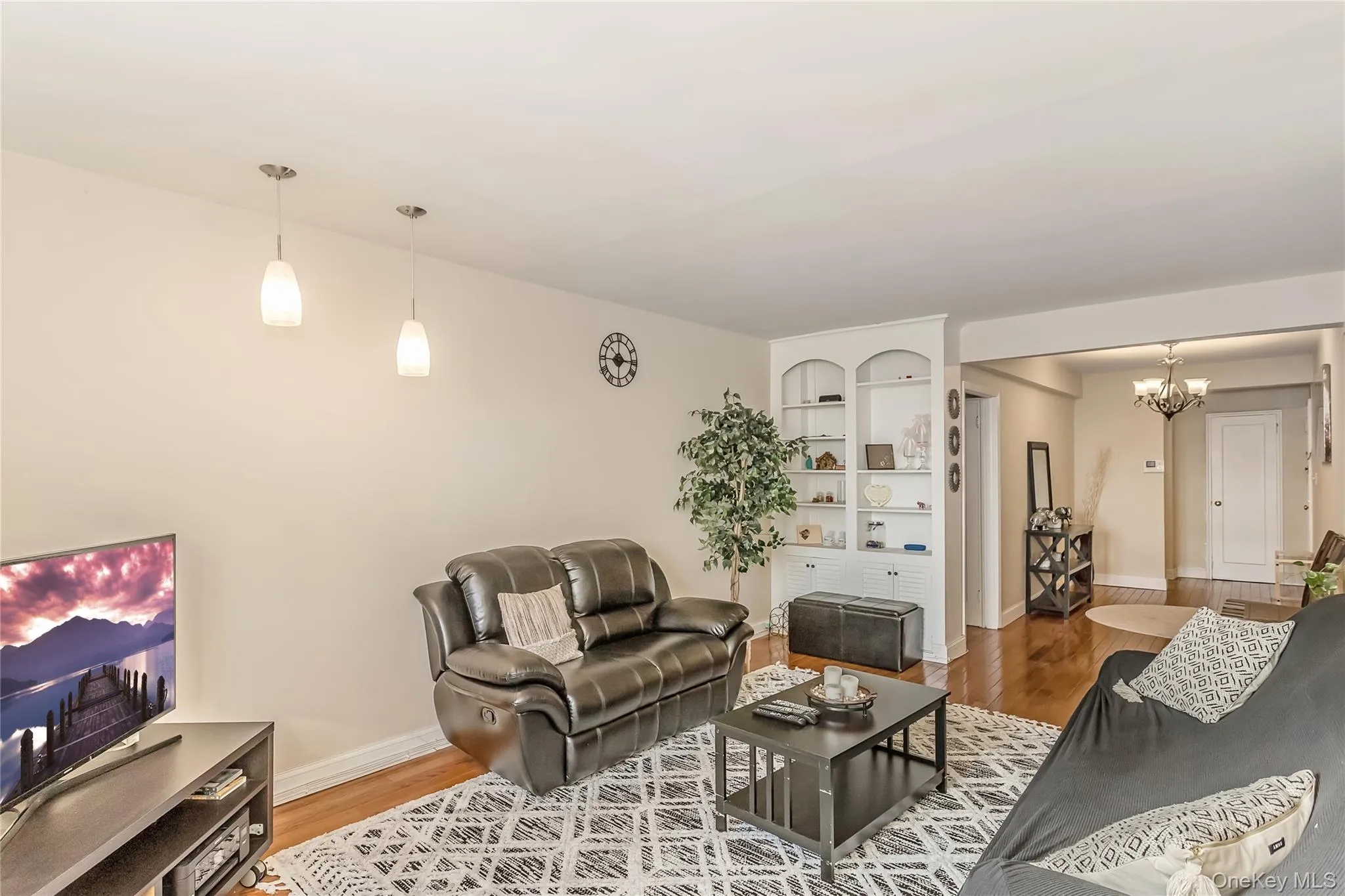 Living area with a notable chandelier, wood finished floors, and baseboards Living area with a notable chandelier, wood finished floors, and baseboards