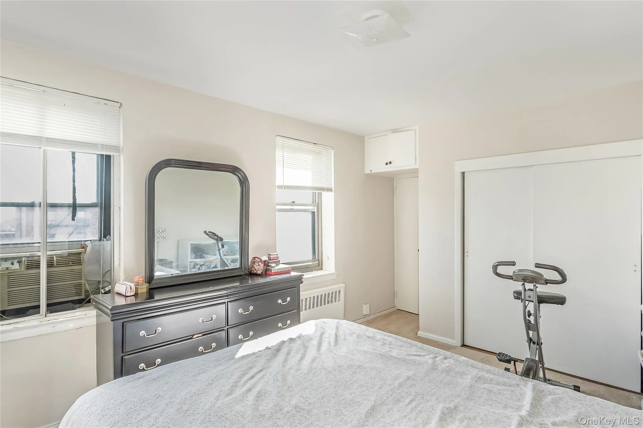 Bedroom with radiator heating unit, cooling unit, and a closet Bedroom with radiator heating unit, cooling unit, and a closet