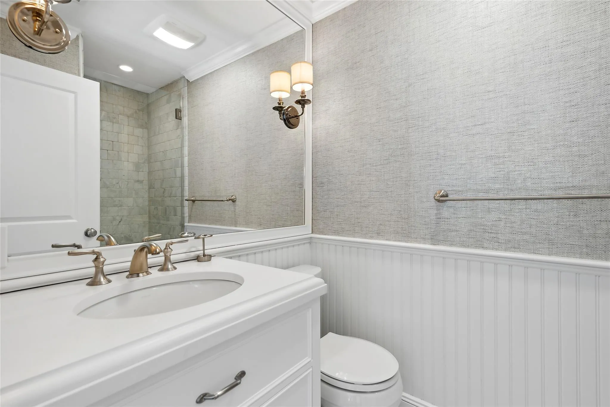 Full bathroom featuring tiled shower, vanity, toilet, and wainscoting Full bathroom featuring tiled shower, vanity, toilet, and wainscoting
