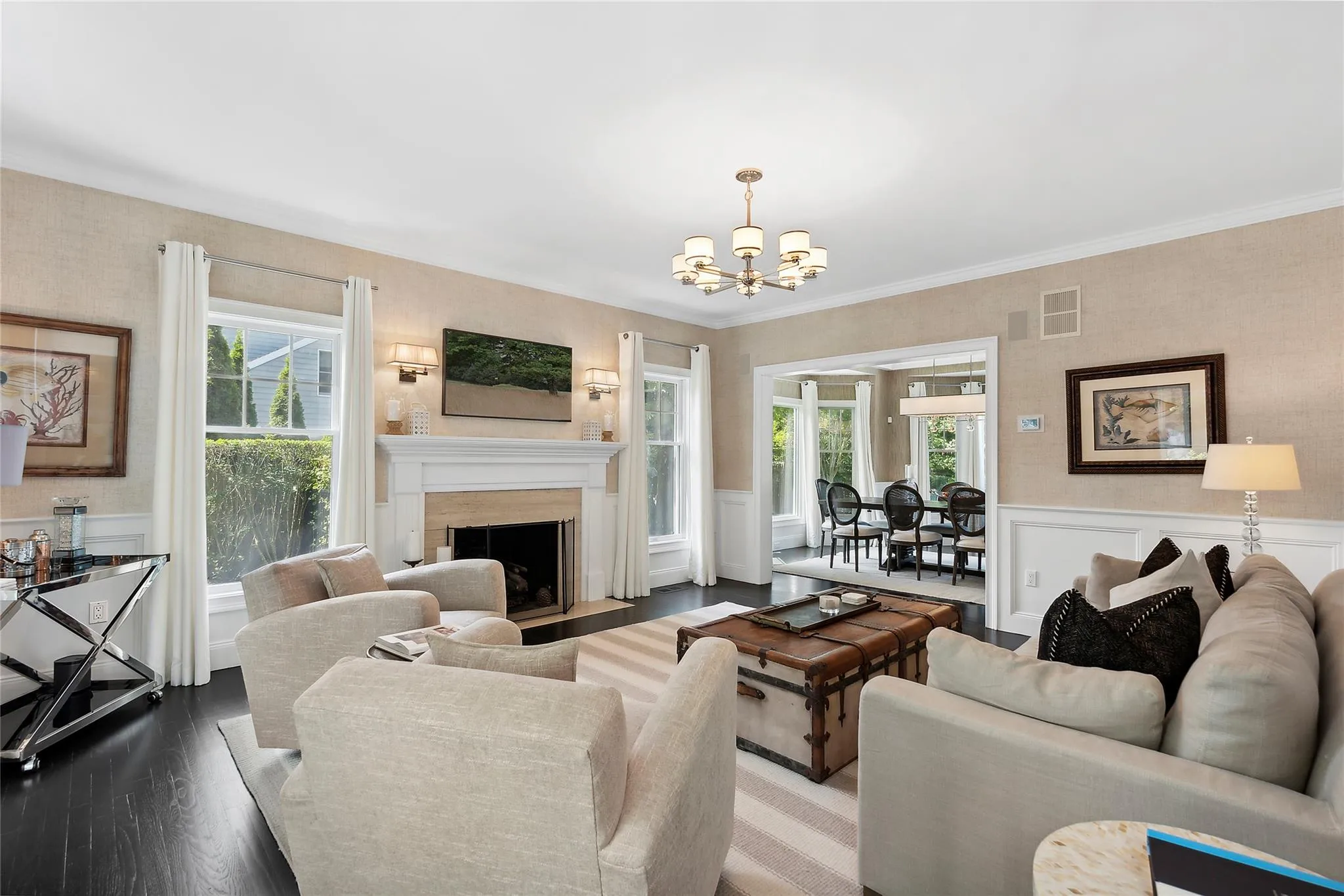 Living room with a fireplace, wood finished floors, wainscoting, and a chandelier Living room with a fireplace, wood finished floors, wainscoting, and a chandelier