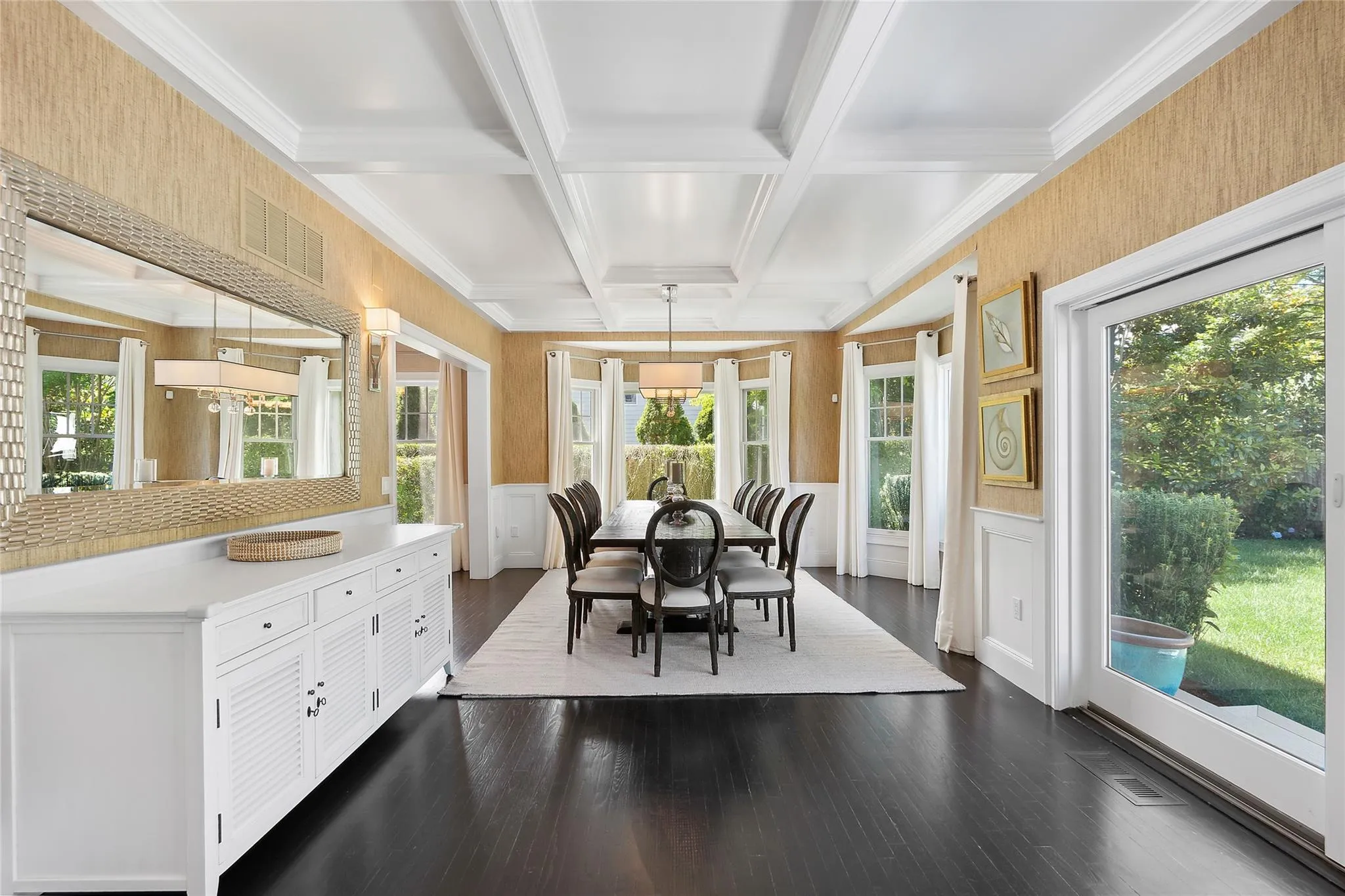 Dining room with beamed ceiling, a wainscoted wall, ornamental molding, dark wood-style floors, and coffered ceiling Dining room with beamed ceiling, a wainscoted wall, ornamental molding, dark wood-style floors, and coffered ceiling