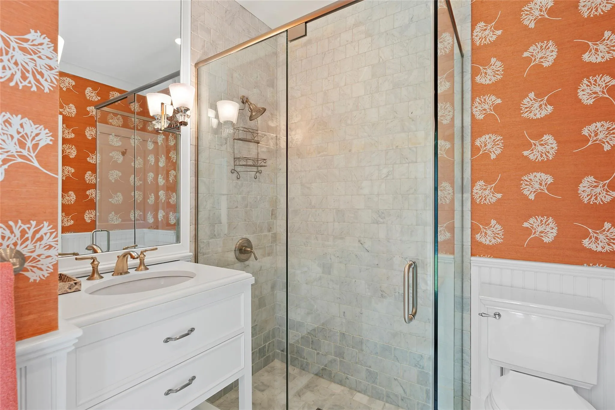Full bathroom with wallpapered walls, toilet, wainscoting, a stall shower, and vanity Full bathroom with wallpapered walls, toilet, wainscoting, a stall shower, and vanity