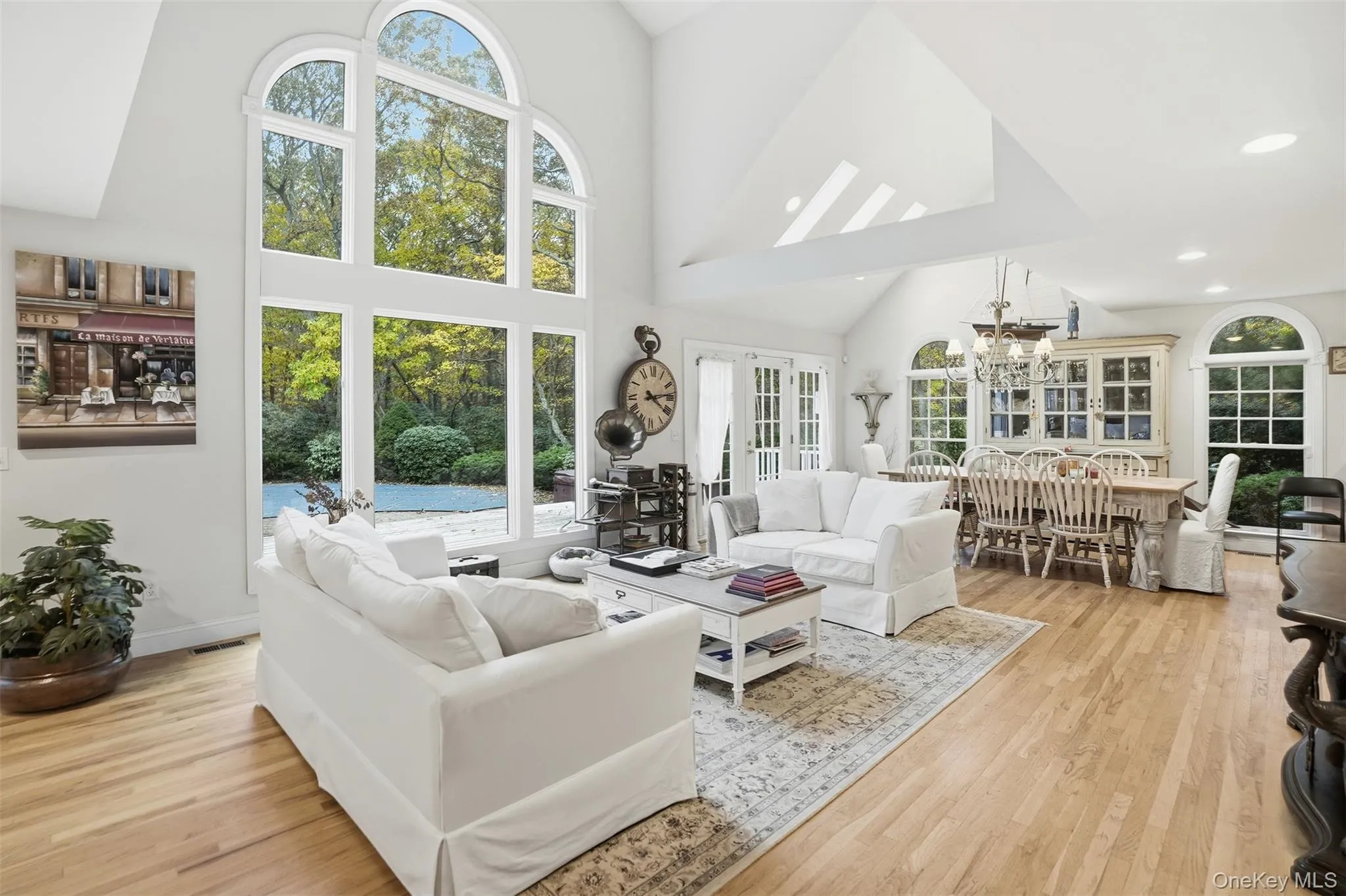 Living room with high vaulted ceiling, healthy amount of natural light, light wood-style floors, a chandelier, and recessed lighting Living room with high vaulted ceiling, healthy amount of natural light, light wood-style floors, a chandelier, and recessed lighting