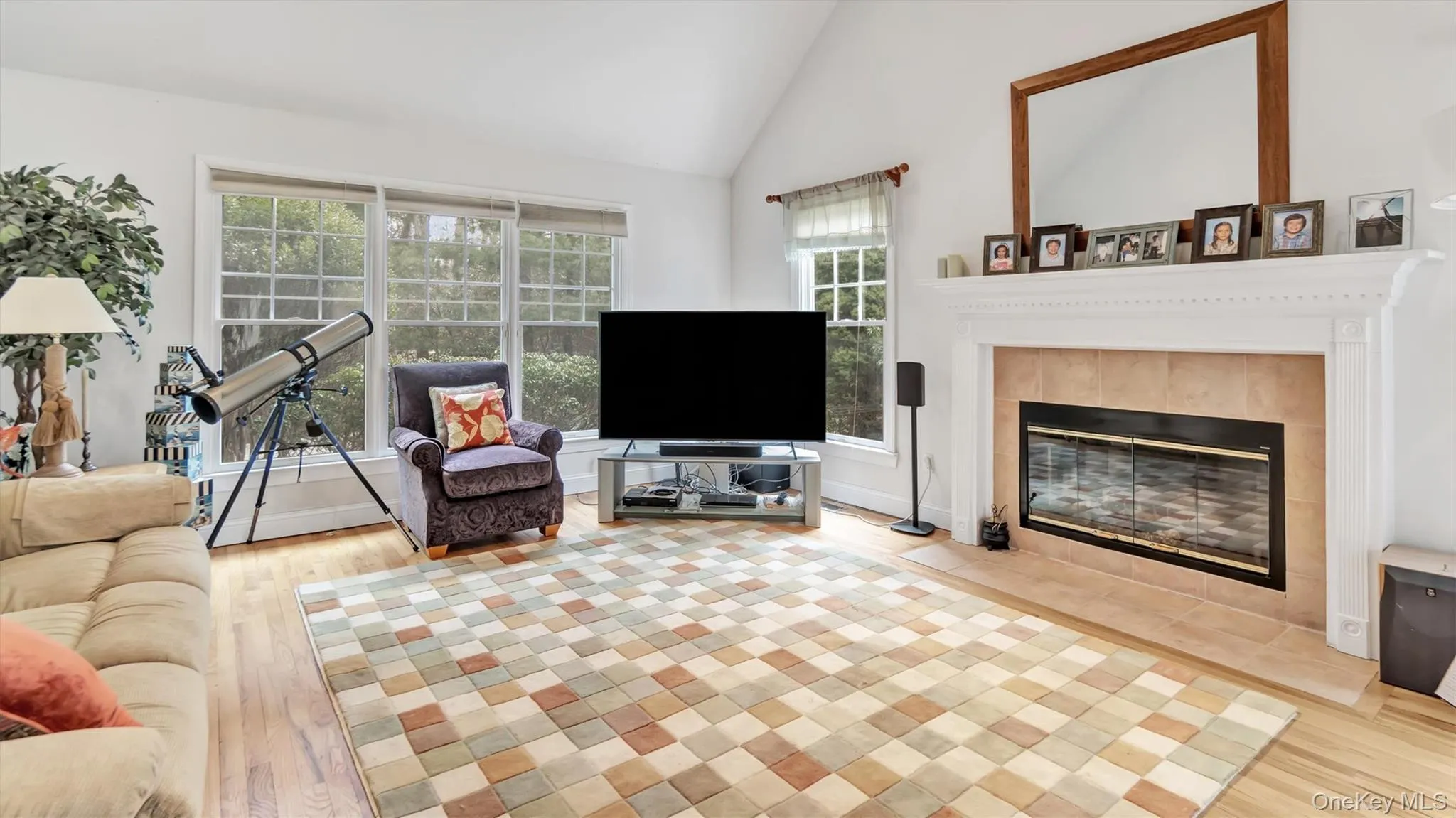 Living area with vaulted ceiling, wood finished floors, and a tile fireplace Living area with vaulted ceiling, wood finished floors, and a tile fireplace