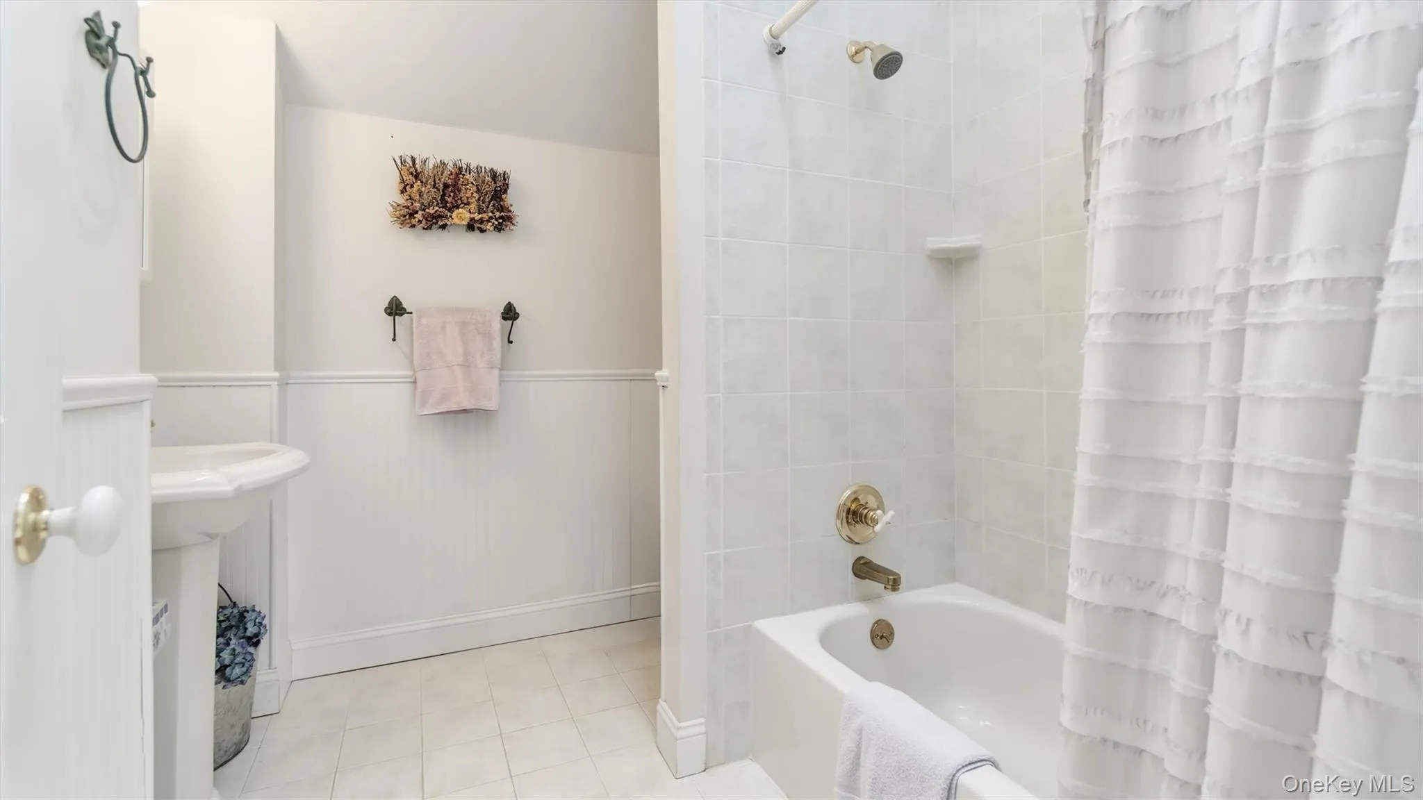Full bath featuring tile patterned floors, a wainscoted wall, and shower / tub combo Full bath featuring tile patterned floors, a wainscoted wall, and shower / tub combo