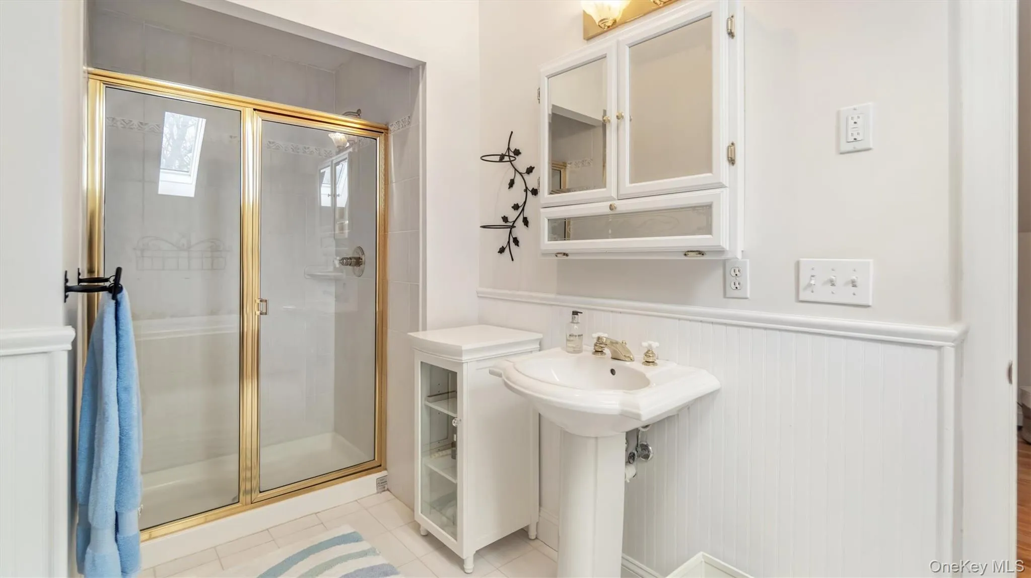 Bathroom featuring a shower stall, a wainscoted wall, and tile patterned floors Bathroom featuring a shower stall, a wainscoted wall, and tile patterned floors