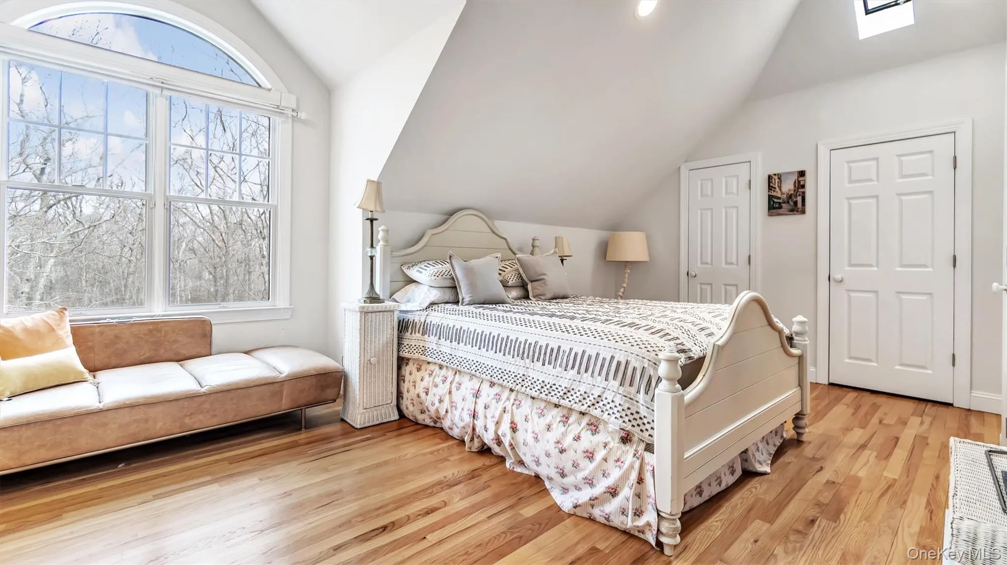 Bedroom with vaulted ceiling with skylight and light wood-style flooring Bedroom with vaulted ceiling with skylight and light wood-style flooring