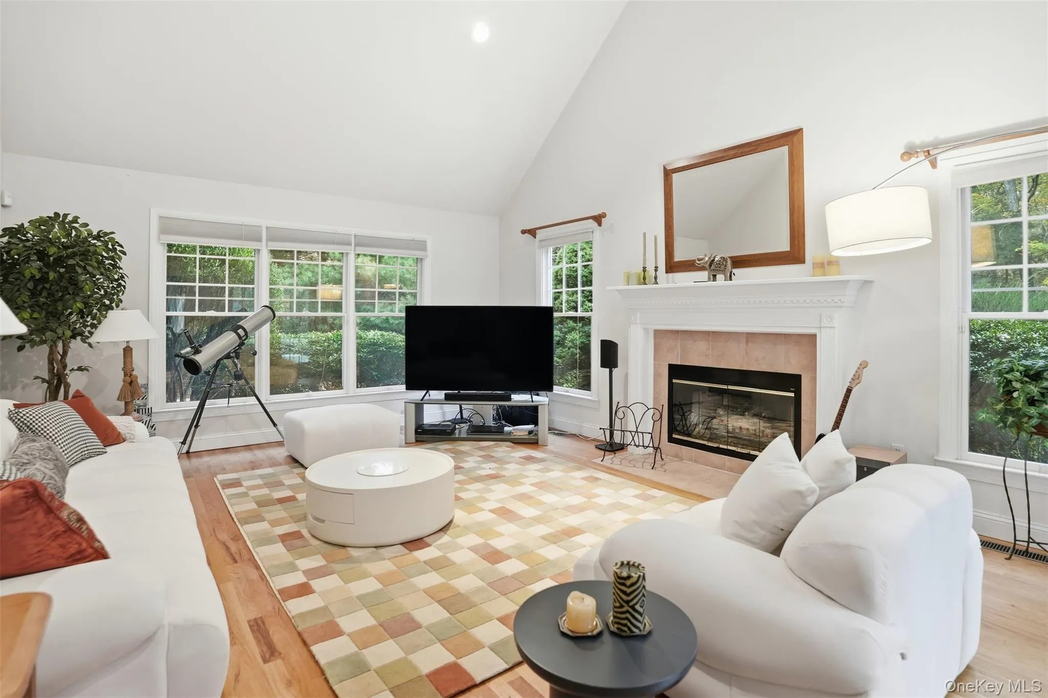 Living room with high vaulted ceiling, a tile fireplace, light wood-style flooring, and recessed lighting Living room with high vaulted ceiling, a tile fireplace, light wood-style flooring, and recessed lighting