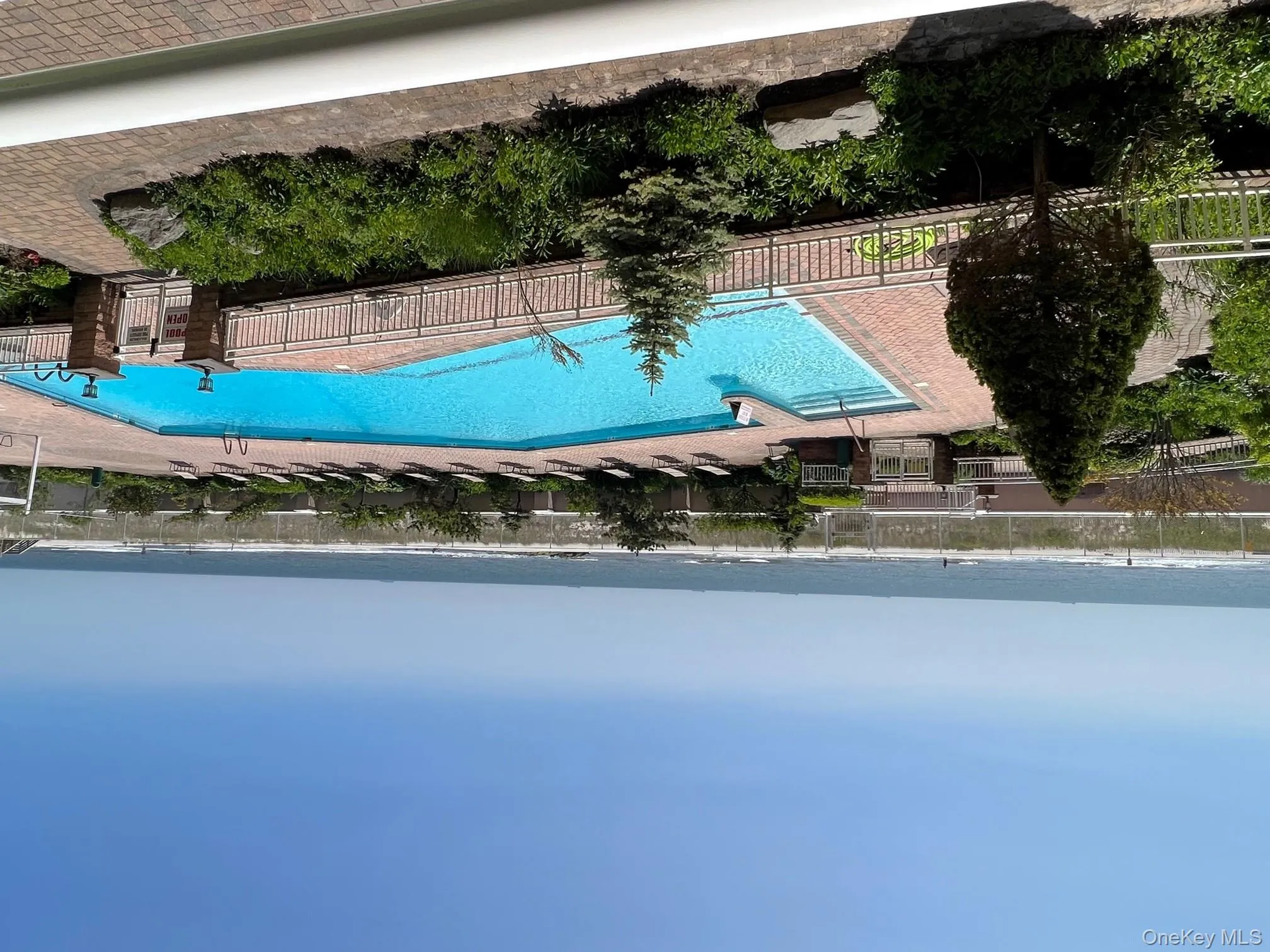 Community pool featuring a water view, a patio, and fence Community pool featuring a water view, a patio, and fence