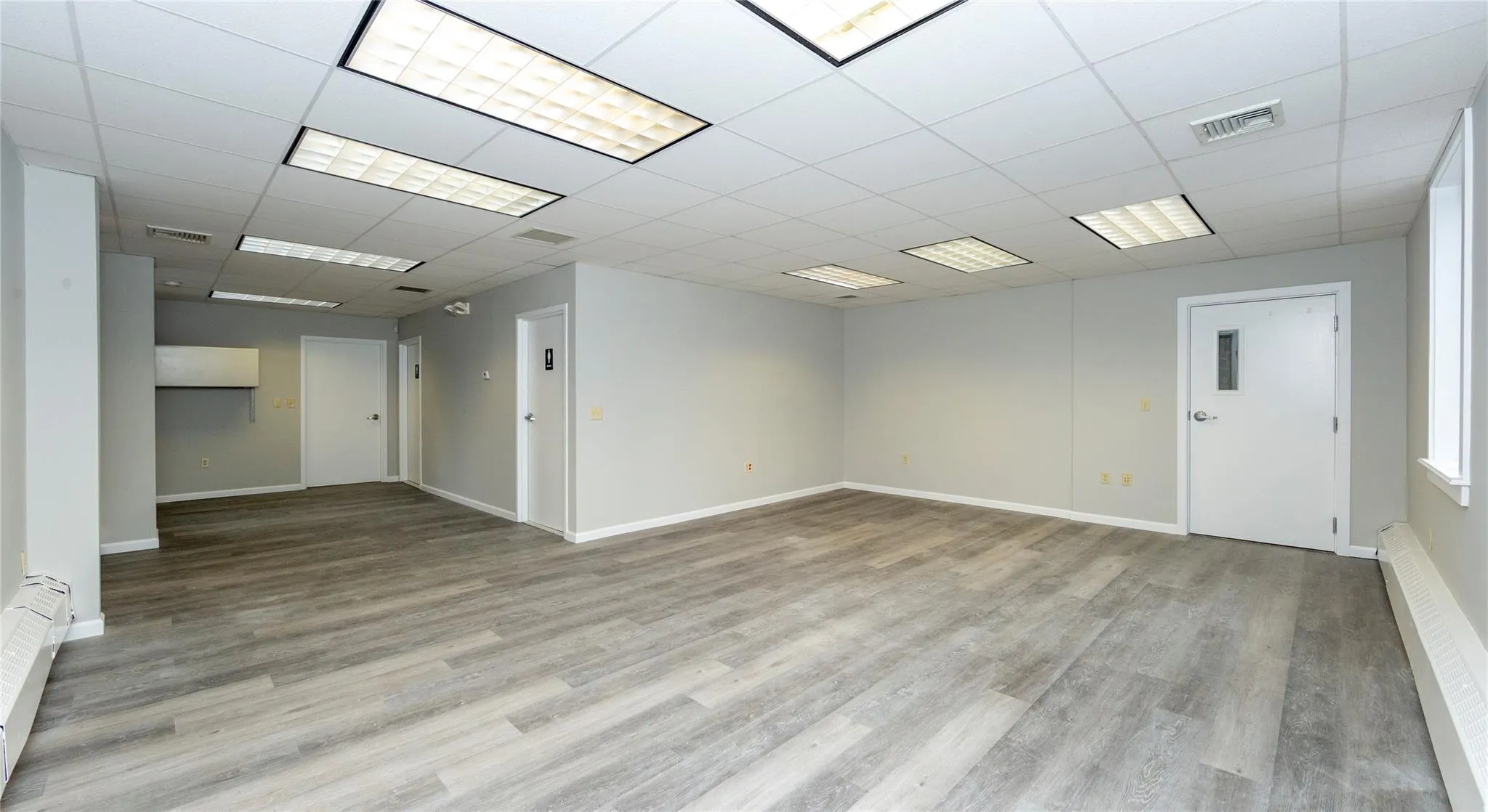 Spare room featuring wood finished floors, visible vents, and a paneled ceiling Spare room featuring wood finished floors, visible vents, and a paneled ceiling