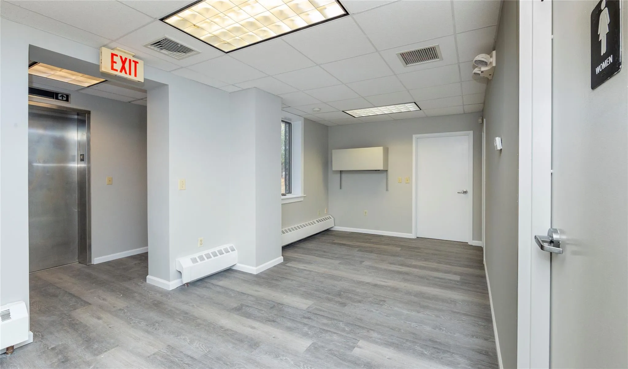 Empty room featuring elevator, visible vents, and a baseboard radiator Empty room featuring elevator, visible vents, and a baseboard radiator