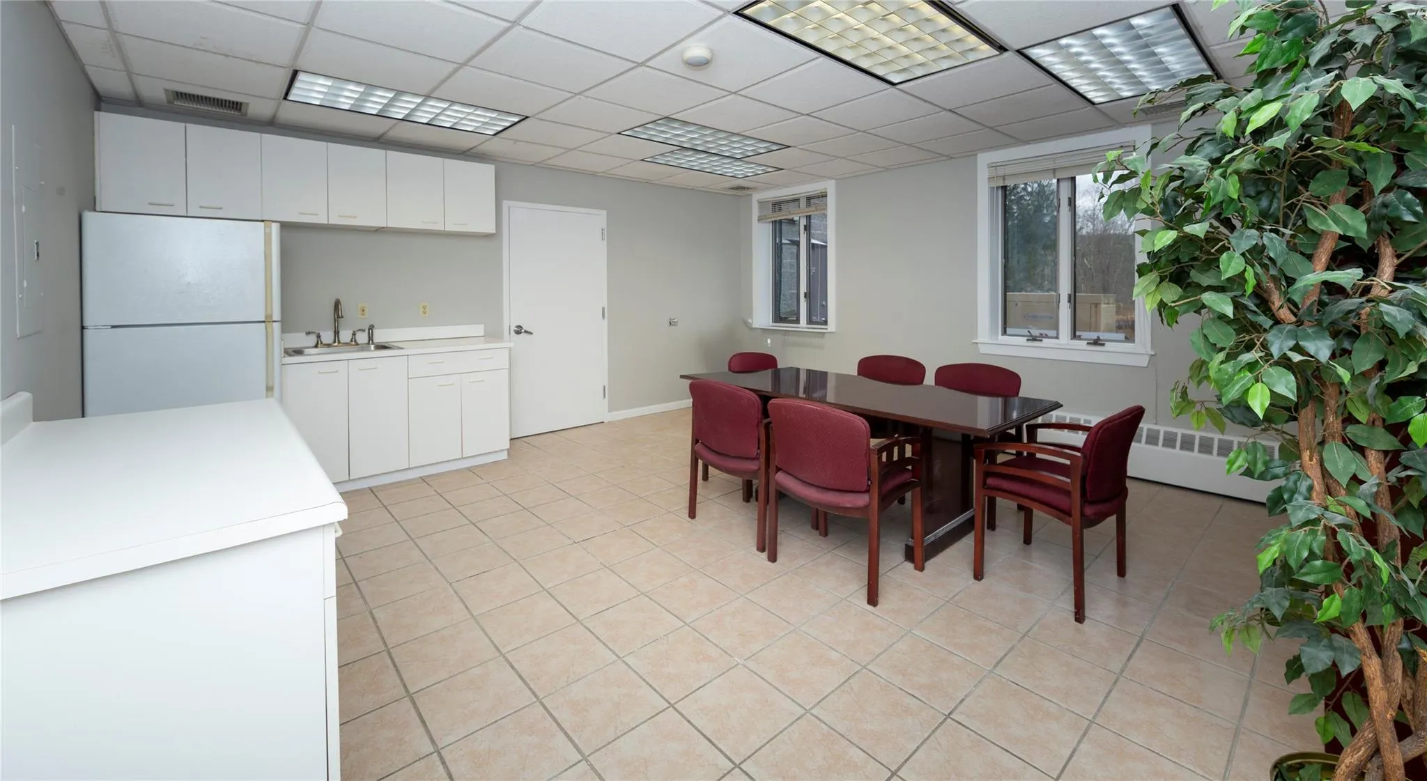 Dining space with light tile patterned floors, visible vents, a paneled ceiling, and radiator heating unit Dining space with light tile patterned floors, visible vents, a paneled ceiling, and radiator heating unit