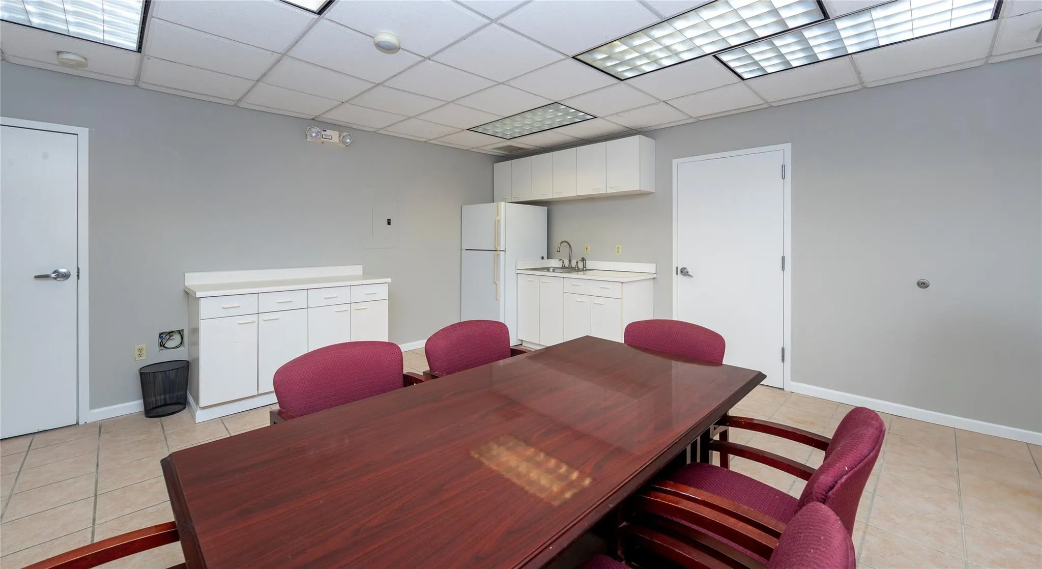 Dining space with light tile patterned floors, baseboards, and a drop ceiling Dining space with light tile patterned floors, baseboards, and a drop ceiling