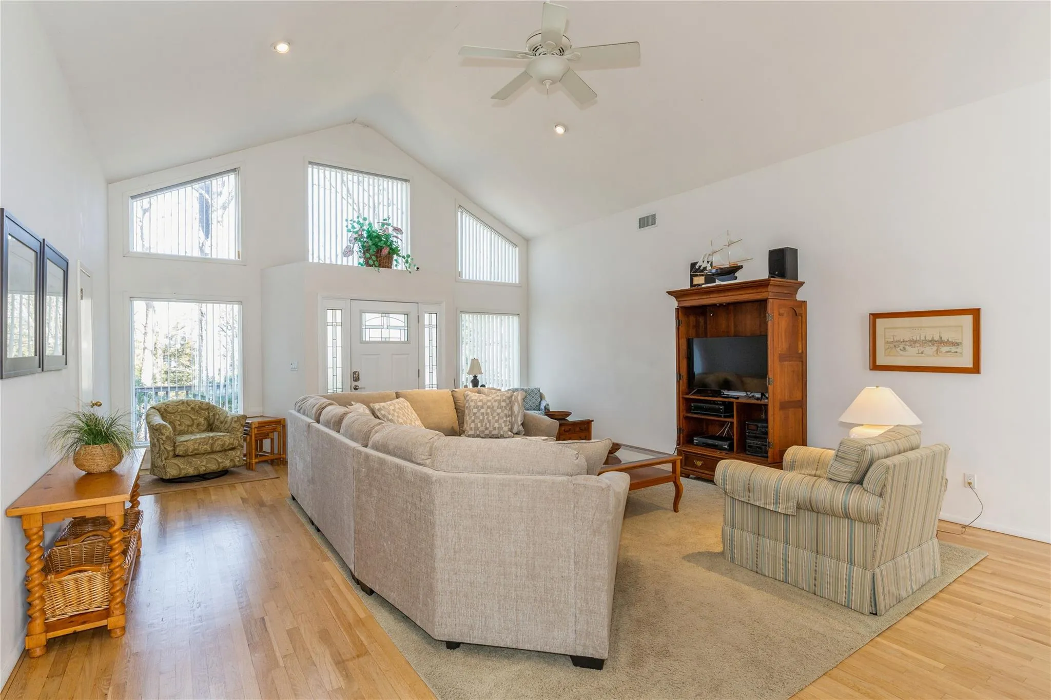Living area with visible vents, ceiling fan, recessed lighting, light wood-style floors, and high vaulted ceiling Living area with visible vents, ceiling fan, recessed lighting, light wood-style floors, and high vaulted ceiling