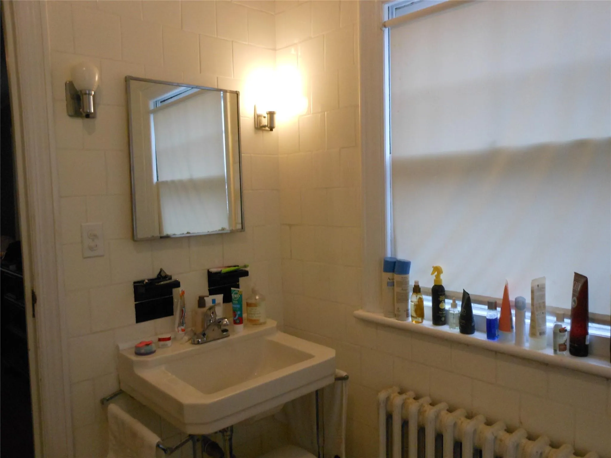 Bathroom featuring a sink, radiator, and tile walls Bathroom featuring a sink, radiator, and tile walls