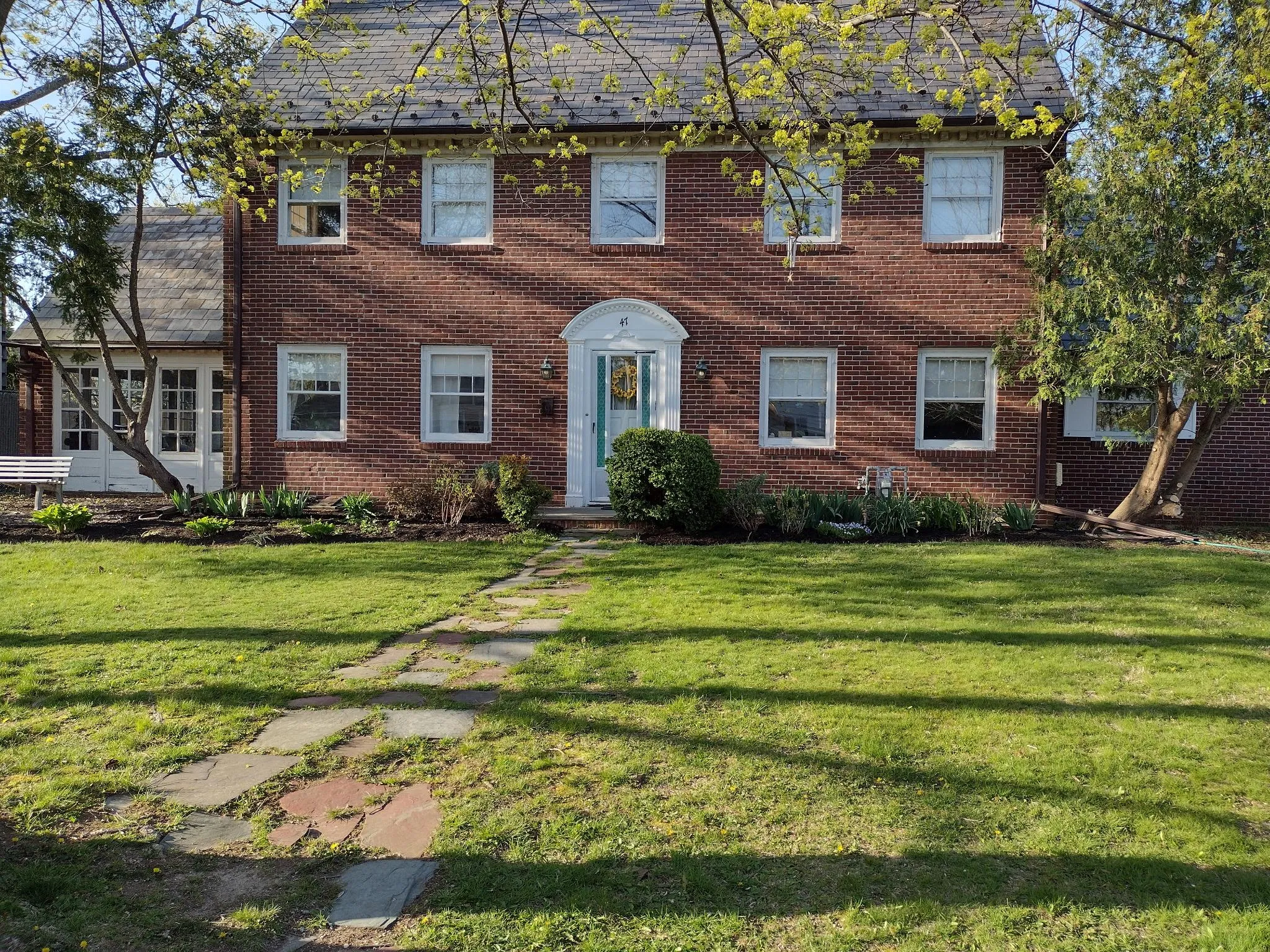 Colonial home featuring brick siding and a front yard Colonial home featuring brick siding and a front yard
