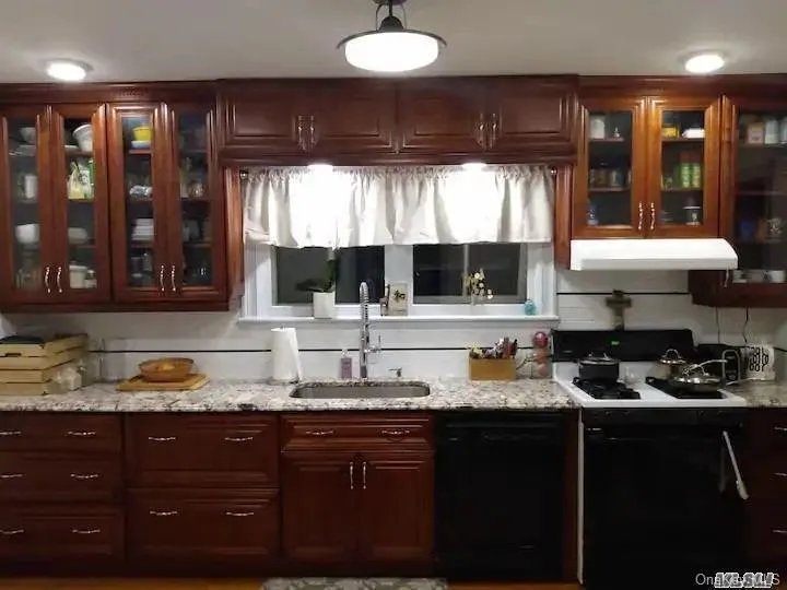 Kitchen with range with gas stovetop, dishwasher, under cabinet range hood, a sink, and light stone counters Kitchen with range with gas stovetop, dishwasher, under cabinet range hood, a sink, and light stone counters