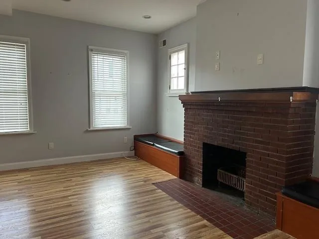 Unfurnished living room featuring wood floors and a fireplace Unfurnished living room featuring wood floors and a fireplace