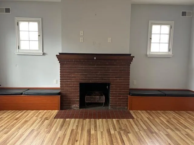 Unfurnished Open Space featuring wood floors and a brick fireplace Unfurnished Open Space featuring wood floors and a brick fireplace