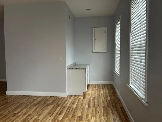 Unfurnished Open Space featuring wood floors, coffee area, multiple windows with natural light Unfurnished Open Space featuring wood floors, coffee area, multiple windows with natural light