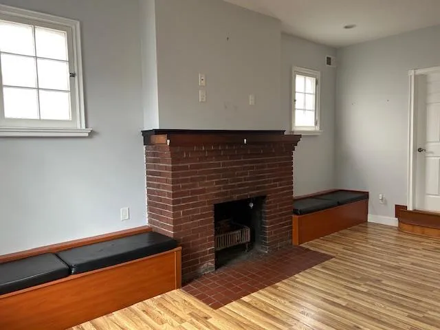 Unfurnished Open Space featuring wood floors and a brick fireplace Unfurnished Open Space featuring wood floors and a brick fireplace