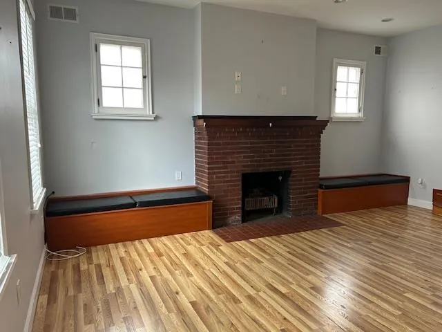 Unfurnished Open Space featuring wood floors and a brick fireplace Unfurnished Open Space featuring wood floors and a brick fireplace