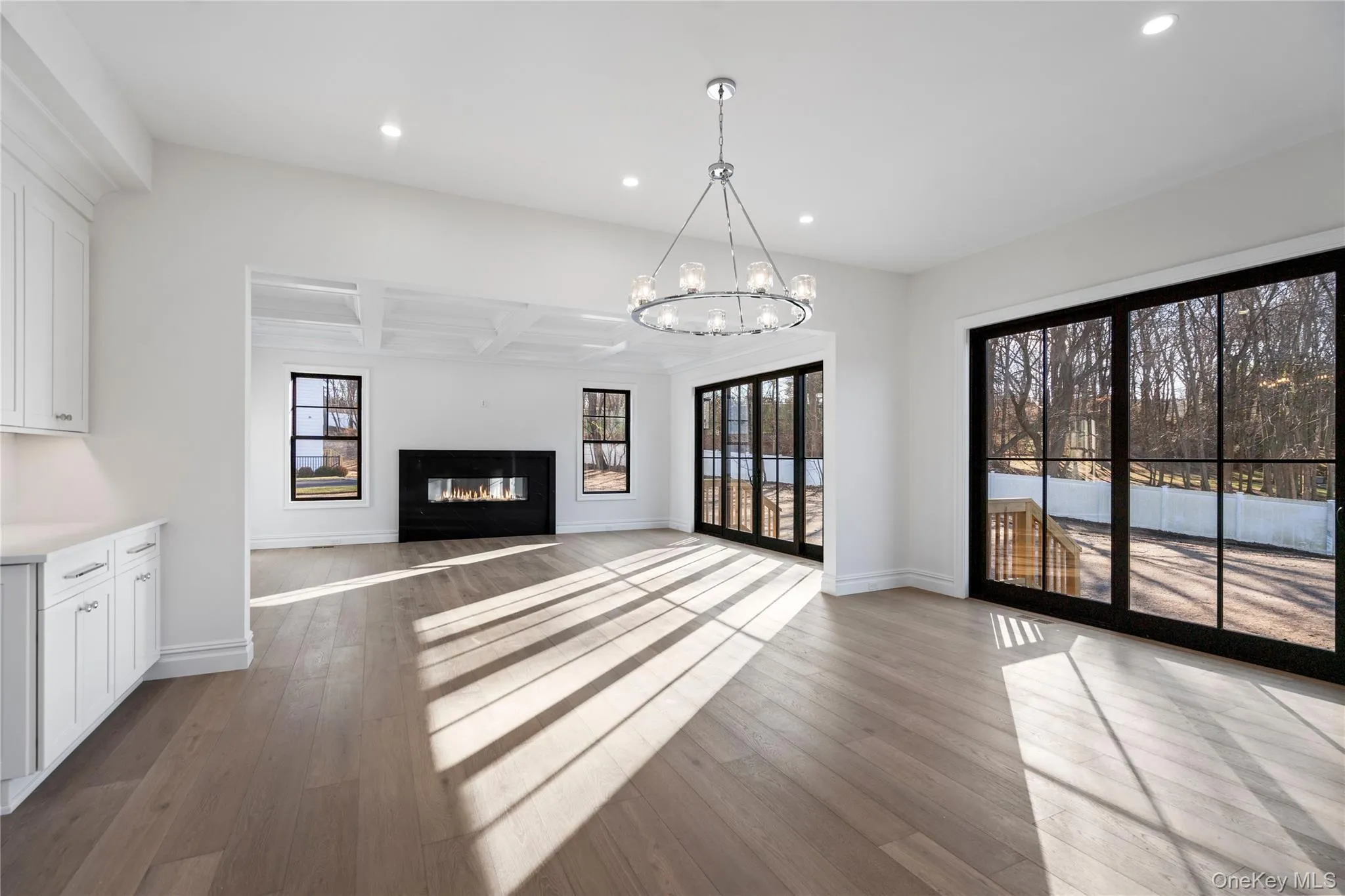 Unfurnished living room featuring recessed lighting, a glass covered fireplace, coffered ceiling, dark wood-type flooring, and beamed ceiling Unfurnished living room featuring recessed lighting, a glass covered fireplace, coffered ceiling, dark wood-type flooring, and beamed ceiling
