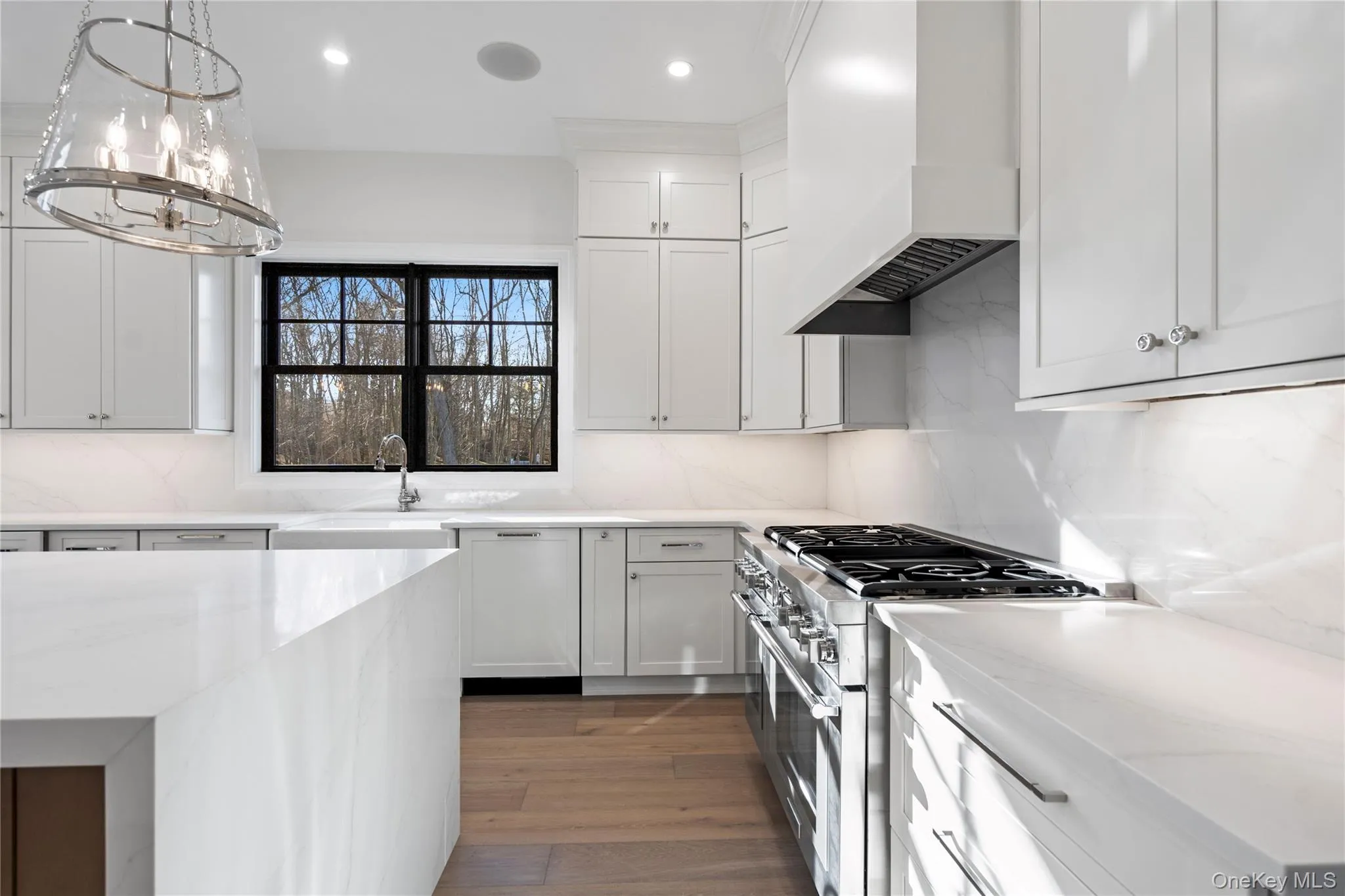 Kitchen with range with two ovens, tasteful backsplash, light stone countertops, premium range hood, and recessed lighting Kitchen with range with two ovens, tasteful backsplash, light stone countertops, premium range hood, and recessed lighting