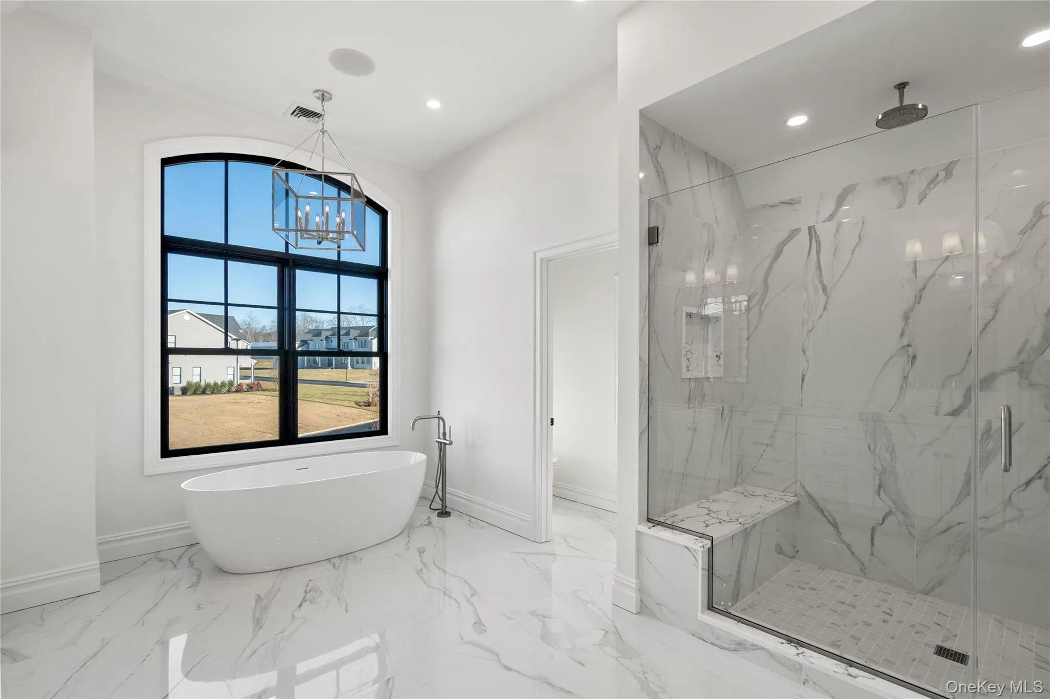Bathroom featuring a marble finish shower, light marble finish flooring, a freestanding bath, recessed lighting, and a chandelier Bathroom featuring a marble finish shower, light marble finish flooring, a freestanding bath, recessed lighting, and a chandelier