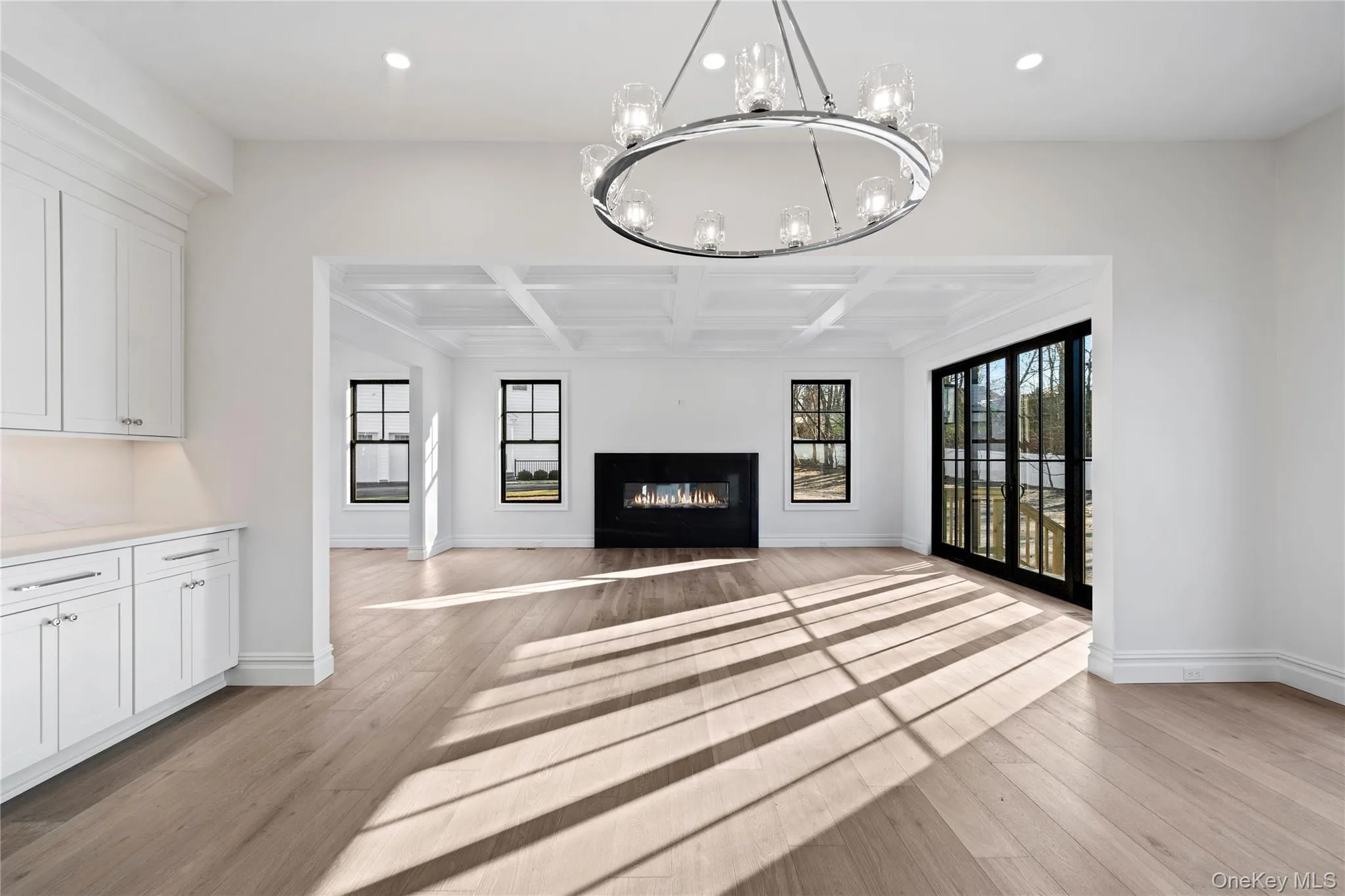 Unfurnished living room with coffered ceiling, beam ceiling, a glass covered fireplace, recessed lighting, and light wood-type flooring Unfurnished living room with coffered ceiling, beam ceiling, a glass covered fireplace, recessed lighting, and light wood-type flooring