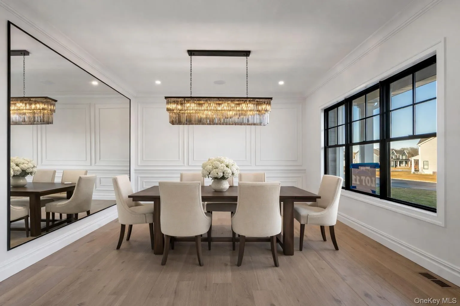 Dining space with a decorative wall, a chandelier, light wood-style floors, and crown molding Dining space with a decorative wall, a chandelier, light wood-style floors, and crown molding