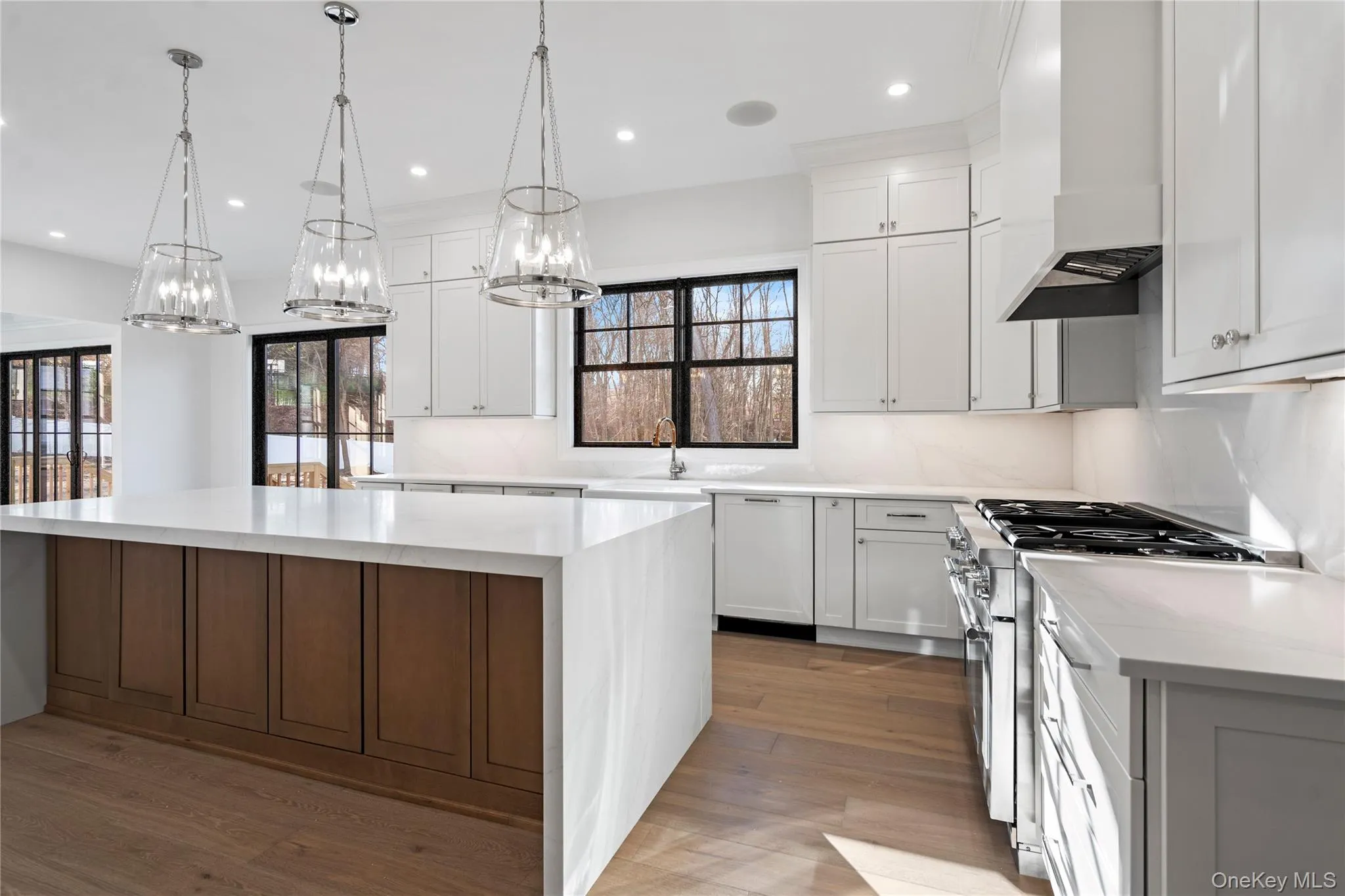 Kitchen with light stone counters, high end stainless steel range, white cabinets, a large island, and recessed lighting Kitchen with light stone counters, high end stainless steel range, white cabinets, a large island, and recessed lighting
