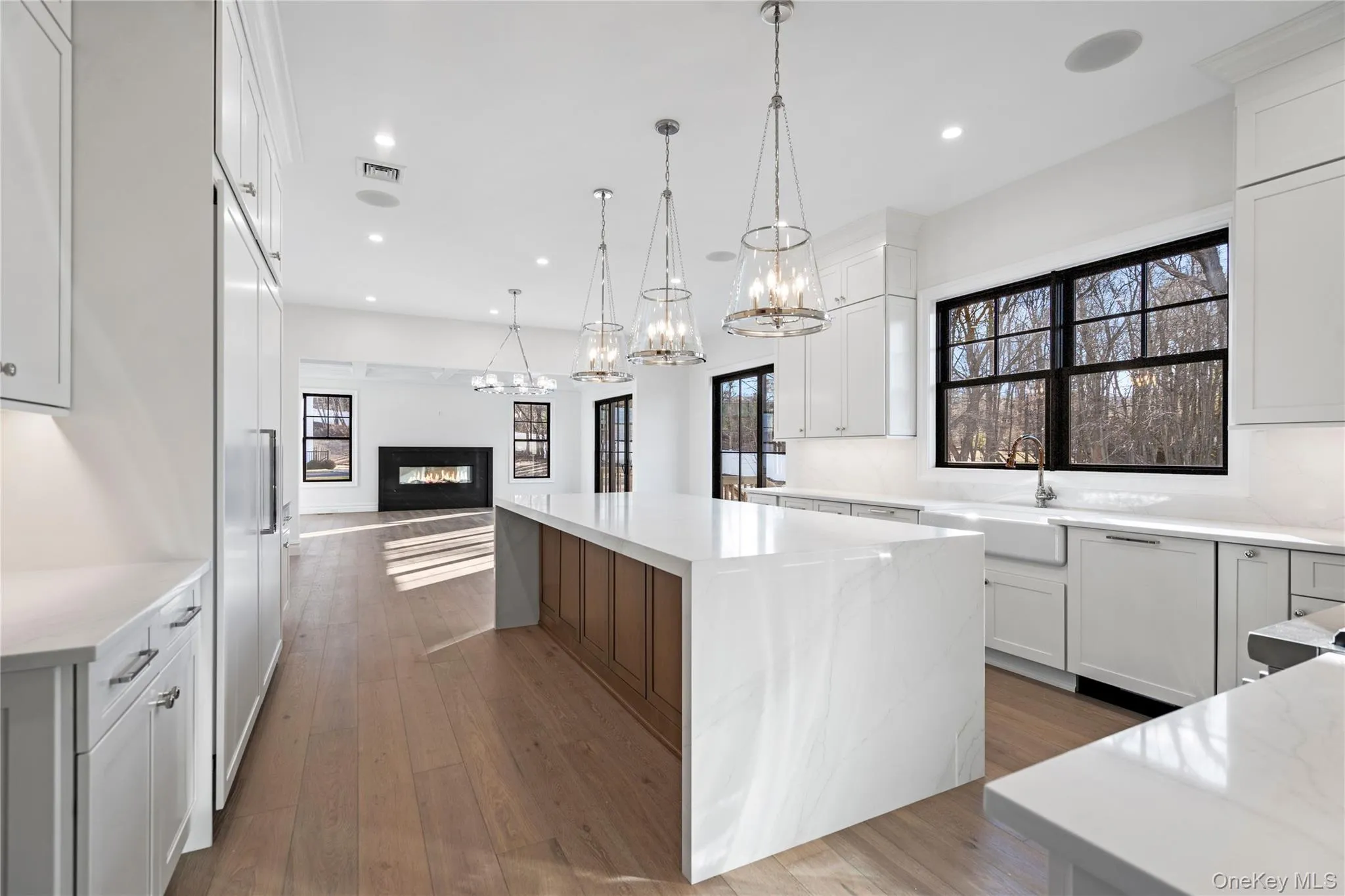 Kitchen with a glass covered fireplace, open floor plan, white cabinets, light stone counters, and recessed lighting Kitchen with a glass covered fireplace, open floor plan, white cabinets, light stone counters, and recessed lighting